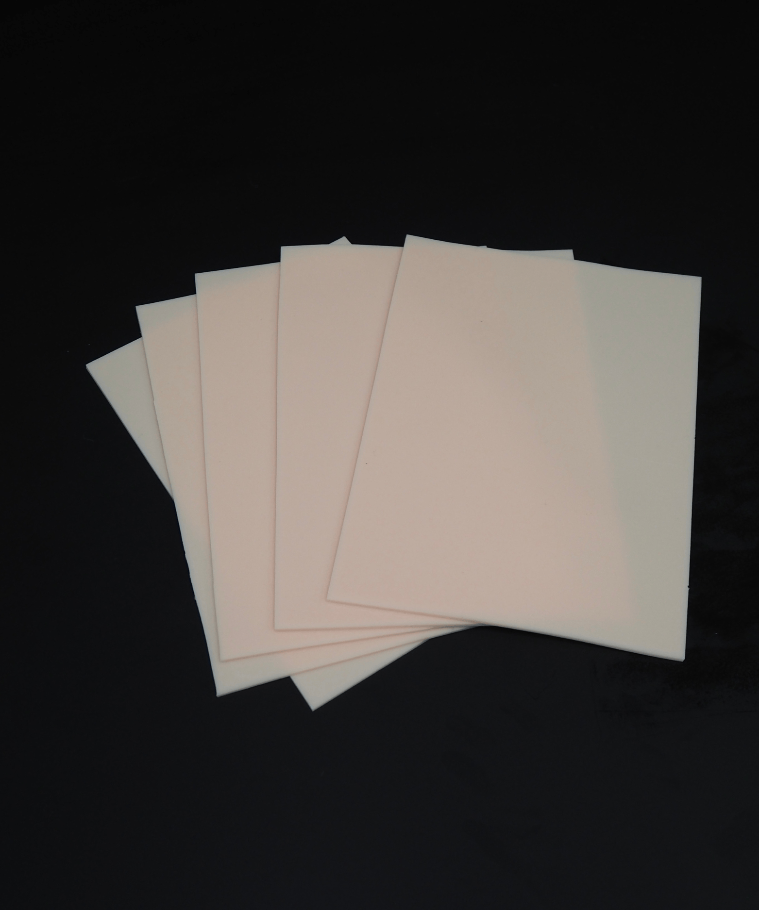 Cinco láminas de NOBLE ART BEAUTY SOCIEDAD LIMITADA «Piel sintética para tatuar de doble cara» (11 x 16 pulgadas) se presentan dispuestas en abanico sobre un fondo negro, ideales para las sesiones de Noble Art o para el cuidado posterior de los piercings.