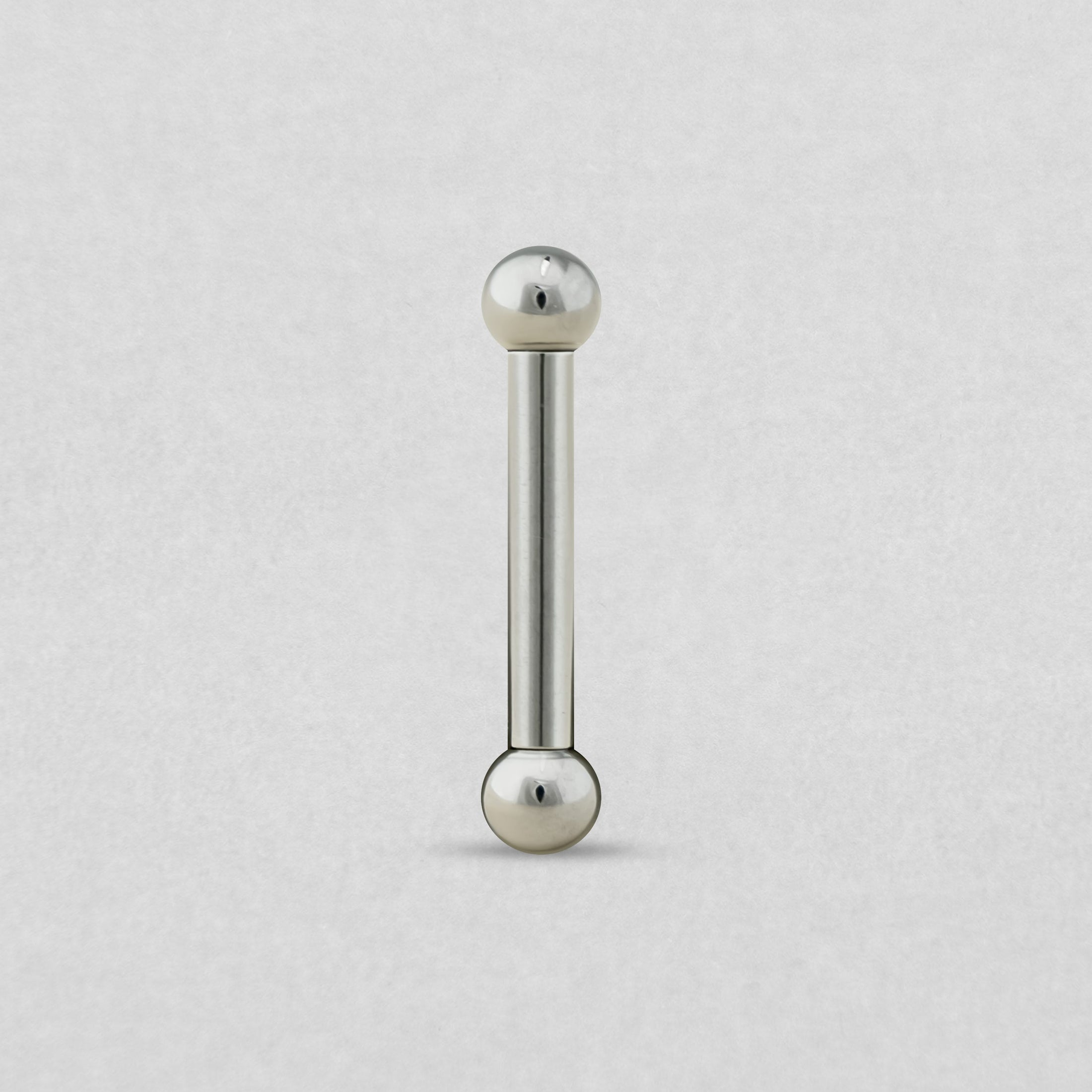 La BARBELL de NOBLE ART BEAUTY SOCIEDAD LIMITADA, con una estructura metálica y extremos esféricos, se muestra en posición vertical sobre un fondo gris claro.