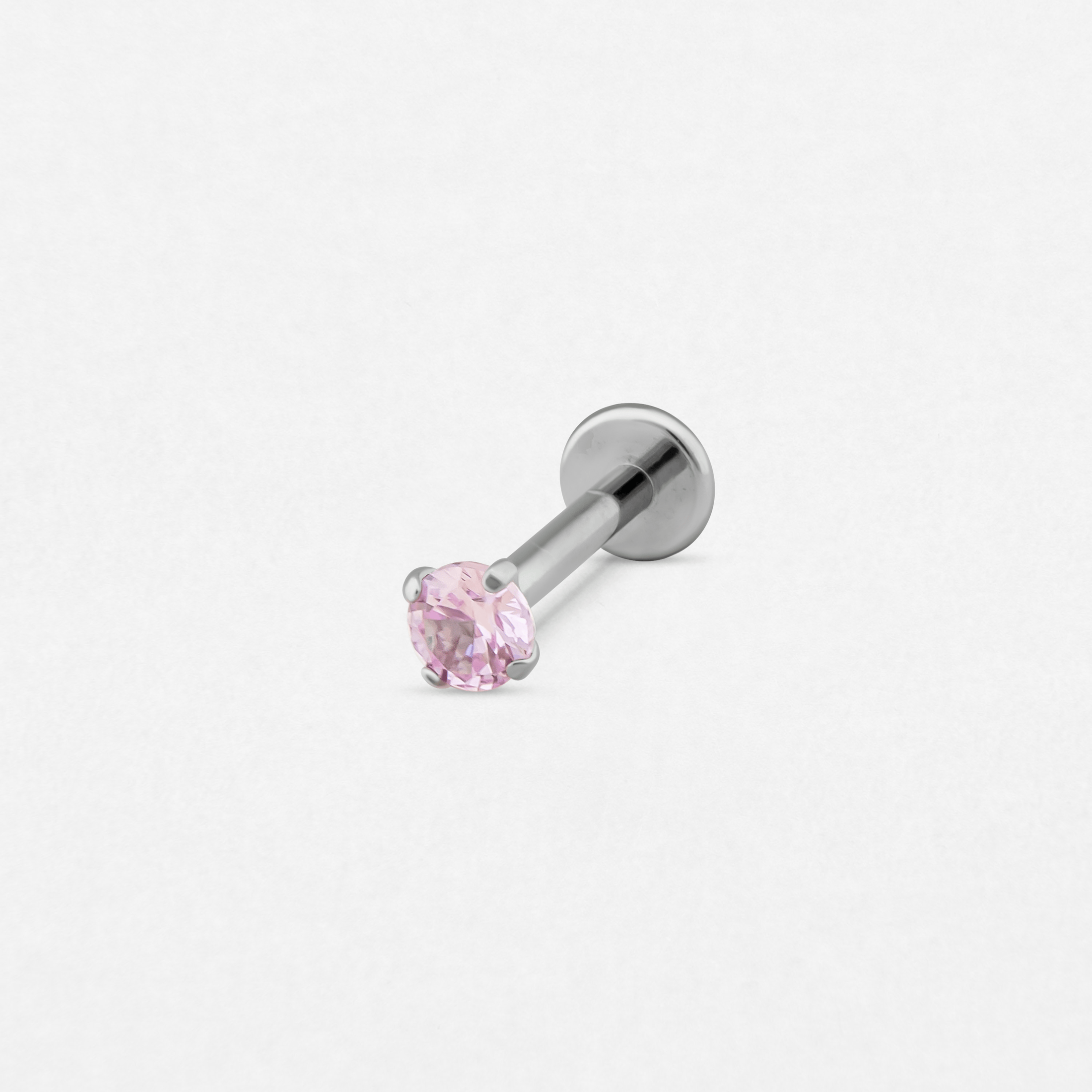 El pendiente de labret «Circonita Rosa» de Titanio-Noble Art presenta una gema rosa redonda y facetada engastada en garras de plata, que destaca con elegancia sobre un fondo blanco.