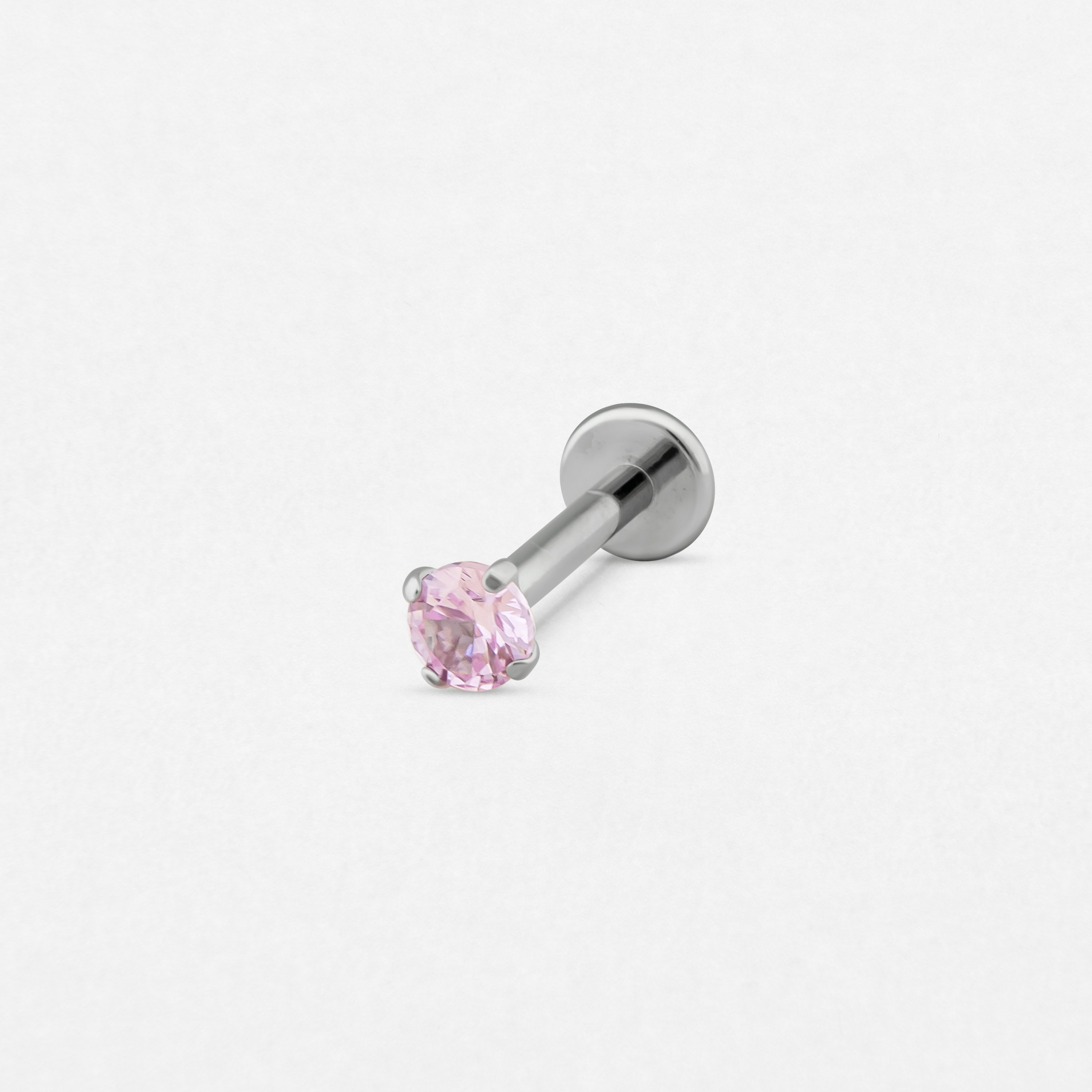 El pendiente de labret «Circonita Rosa» de Titanio-Noble Art presenta una gema rosa redonda y facetada engastada en garras de plata, que destaca con elegancia sobre un fondo blanco.