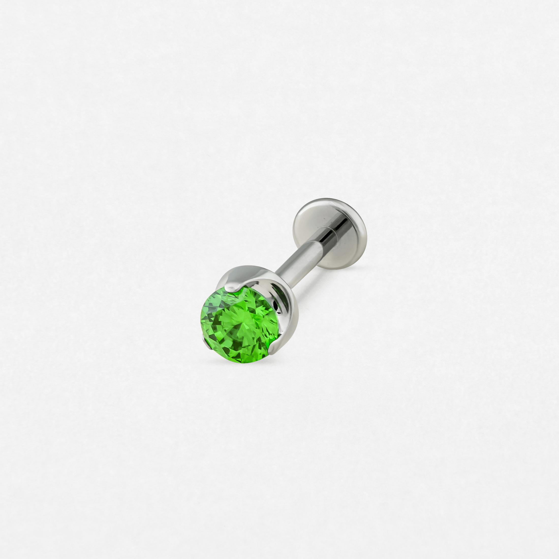El «Circonita verde» de Titanio-Noble Art es un pendiente tipo labret de plata con una gema verde redonda y facetada en un extremo y un disco plano en el otro, que se muestra sobre un fondo blanco liso.