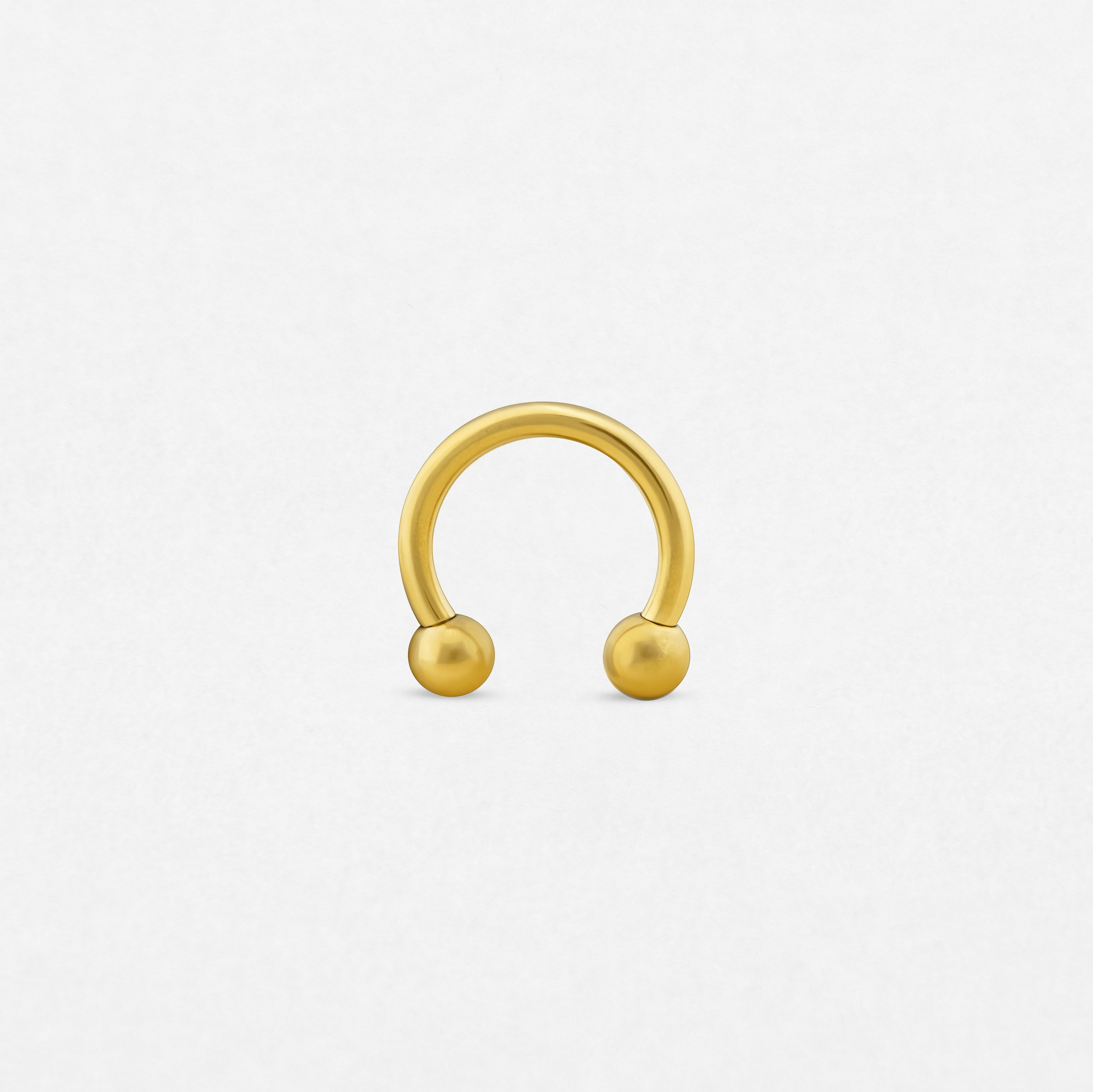A Circular barbell with two round ball ends is displayed upright on a plain white background—ideal for those who value unique piercing styles from Noble Art Miami.