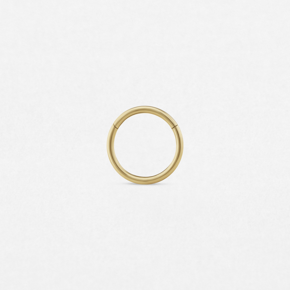 A minimalist seamless gold «Clicker» hoop by Titanio-Noble Art stands out on a plain white background, its simple circular design giving it a refined style.