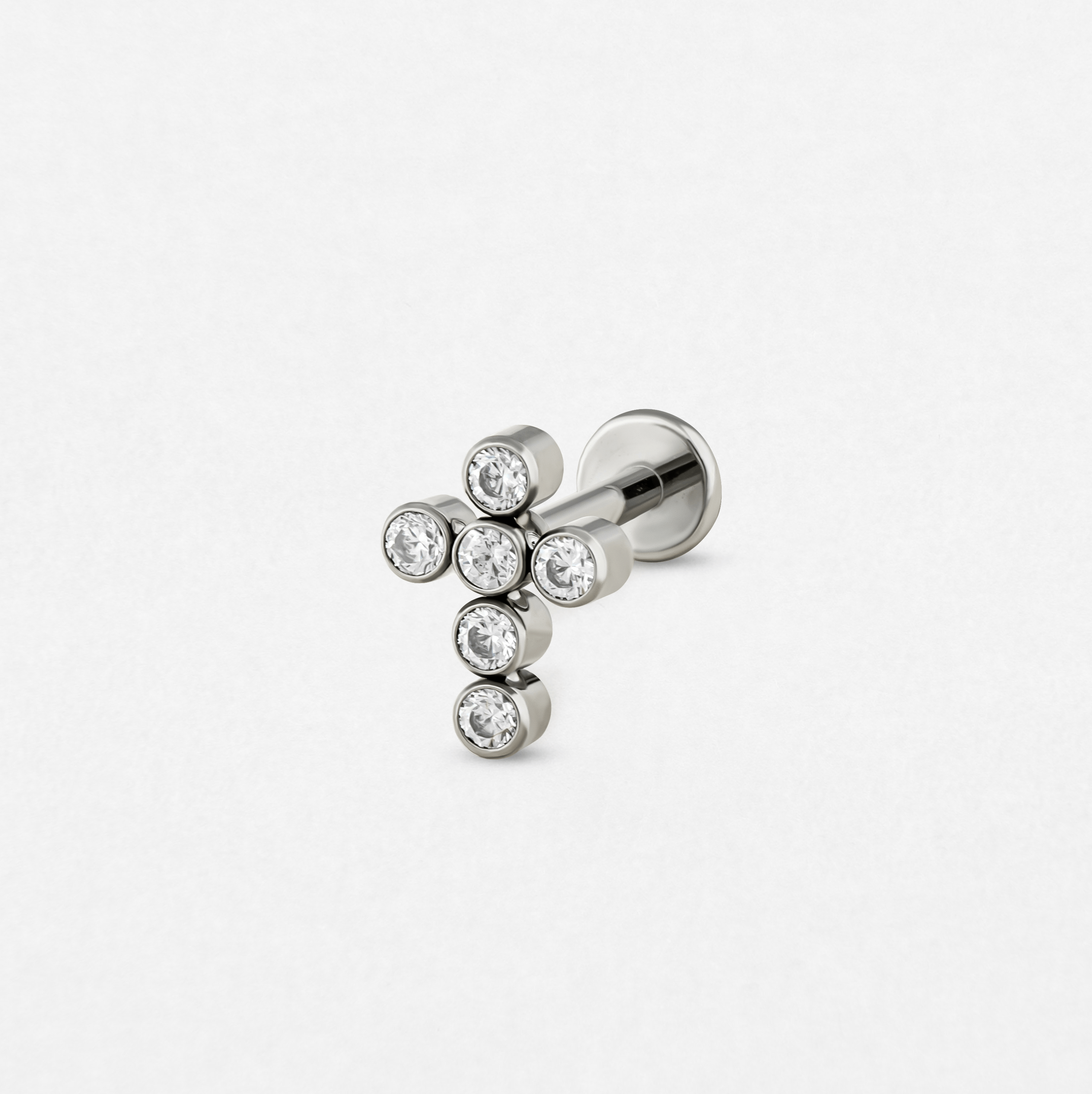 El «Titanio- Noble Art Cross CZ» es un pendiente de botón de plata con forma de cruz y siete piedras preciosas redondas transparentes, perfecto para tu piercing y que se muestra sobre un fondo blanco liso.