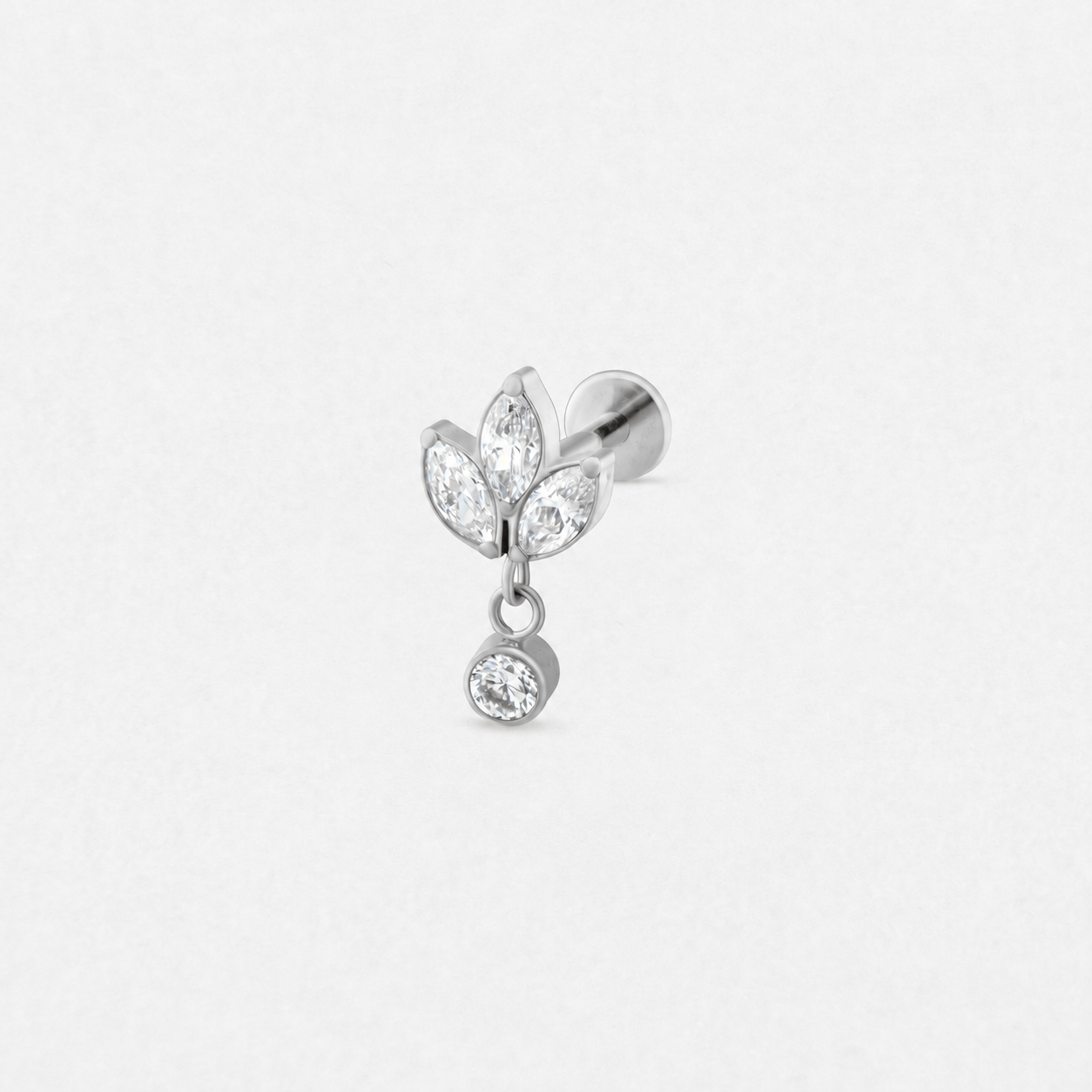El pendiente de botón de plata «Top Charm» de Titanio-Noble Art cuenta con tres engastes en forma de hoja y de corte marquesa con piedras transparentes, además de una única piedra redonda colgante, todo ello presentado sobre un fondo blanco liso.