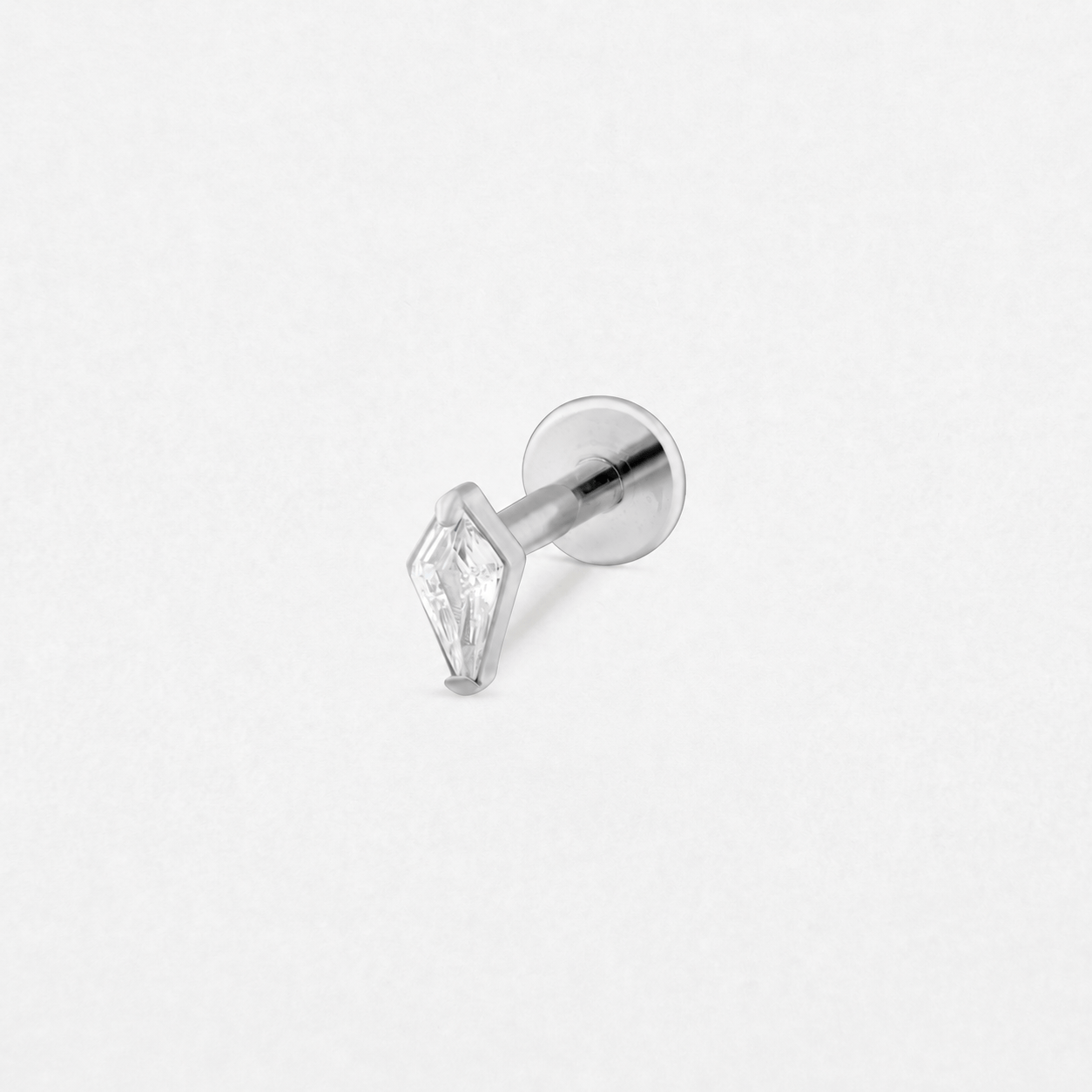 El pendiente tipo labret «Top Egan» de NOBLE ART BEAUTY SOCIEDAD LIMITADA, con acabado plateado y una piedra preciosa transparente en forma de diamante, aparece fotografiado sobre un fondo blanco liso.