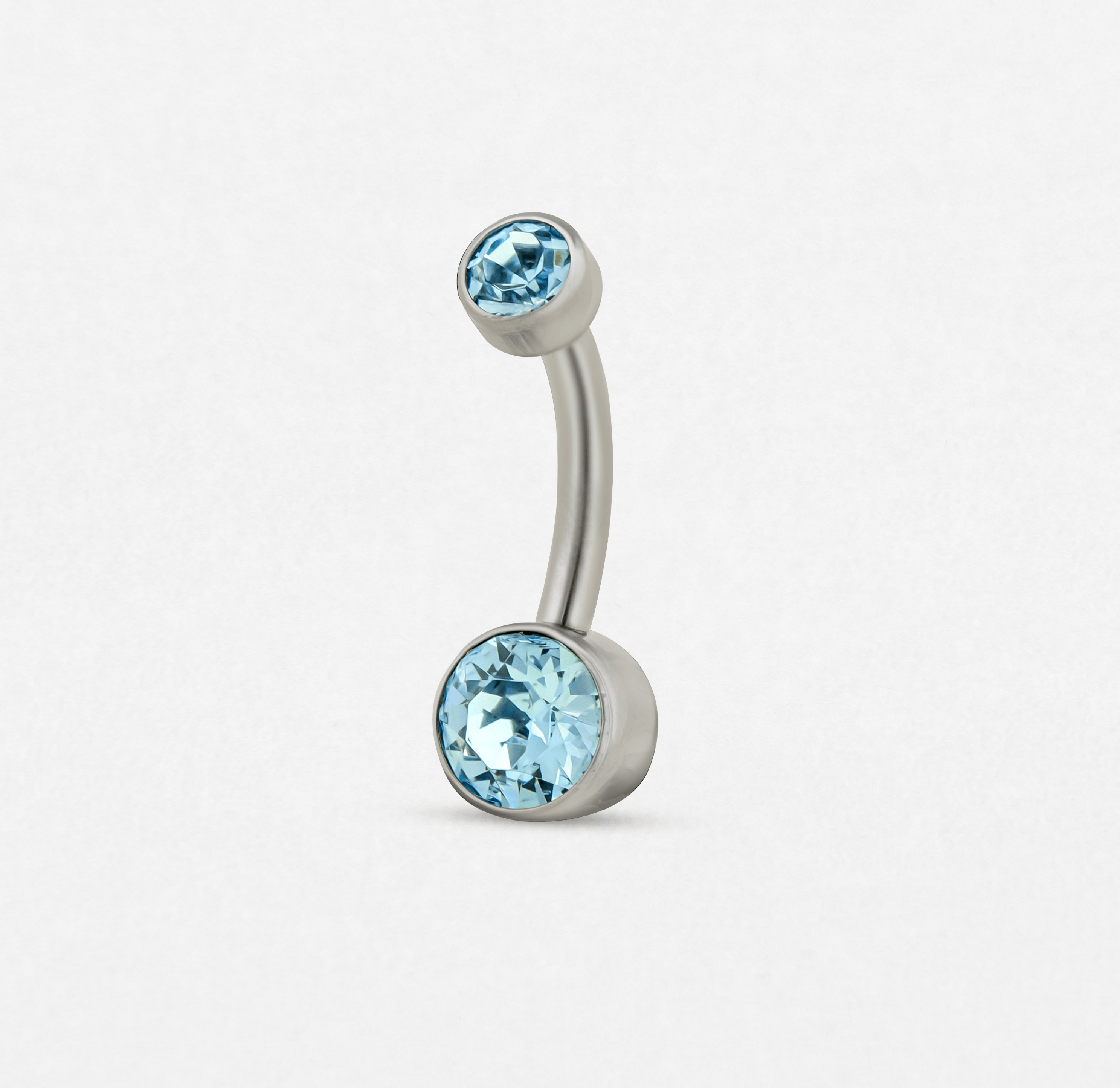 El «Ombligo cz azul» de Titanio-Noble Art es un piercing de ombligo de plata curvado con dos piedras redondas de color azul claro —la de arriba es más pequeña y la de abajo, más grande— que se muestra sobre un fondo blanco.