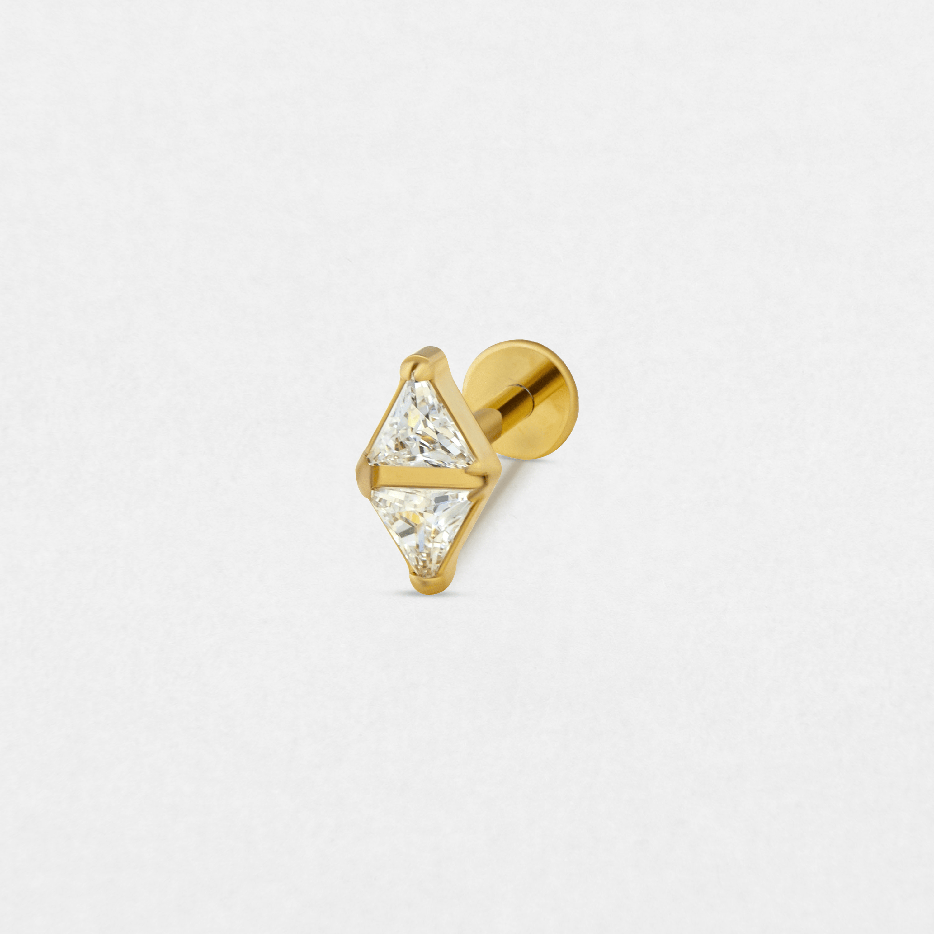 Los pendientes de botón «Anastasia» de Titanio-Noble Art cuentan con dos piedras preciosas transparentes de forma triangular engastadas punta con punta formando un rombo, lo que les confiere una elegancia sutil, perfecta para combinarlos con tu piercing favorito. Se muestran sobre un fondo blanco liso.