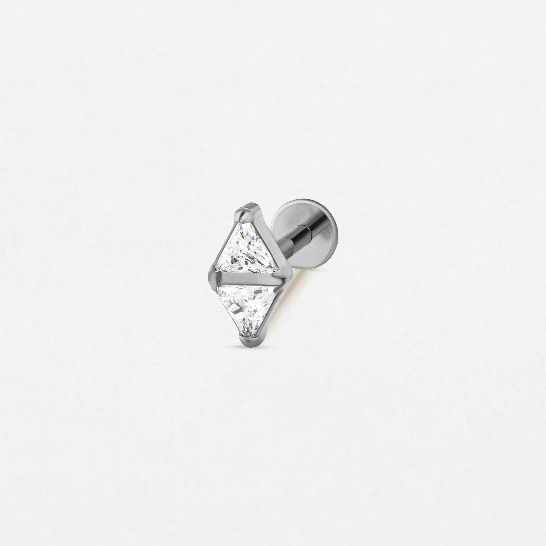 El pendiente «Anastasia» de Titanio-Noble Art cuenta con dos cristales transparentes triangulares engastados en forma de rombo sobre un pendiente de botón de plata con la parte trasera plana, ideal para perforaciones elegantes. Se muestra sobre un fondo blanco liso.