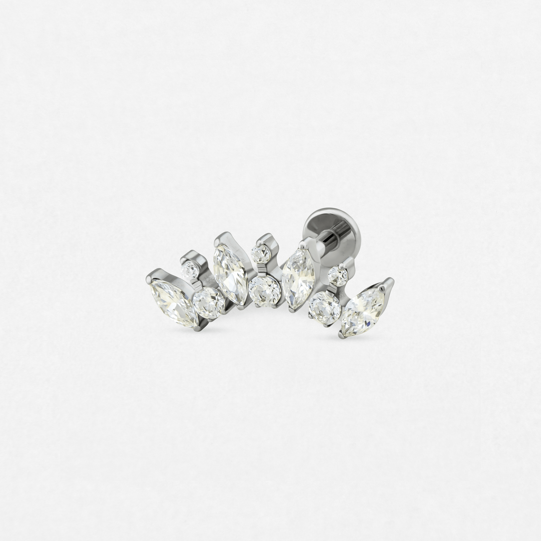 El modelo «Apolo» de Titanio-Noble Art es un pendiente de botón de plata con piedras preciosas transparentes de talla marquesa y redonda, con un diseño curvo, que se muestra sobre un fondo blanco.