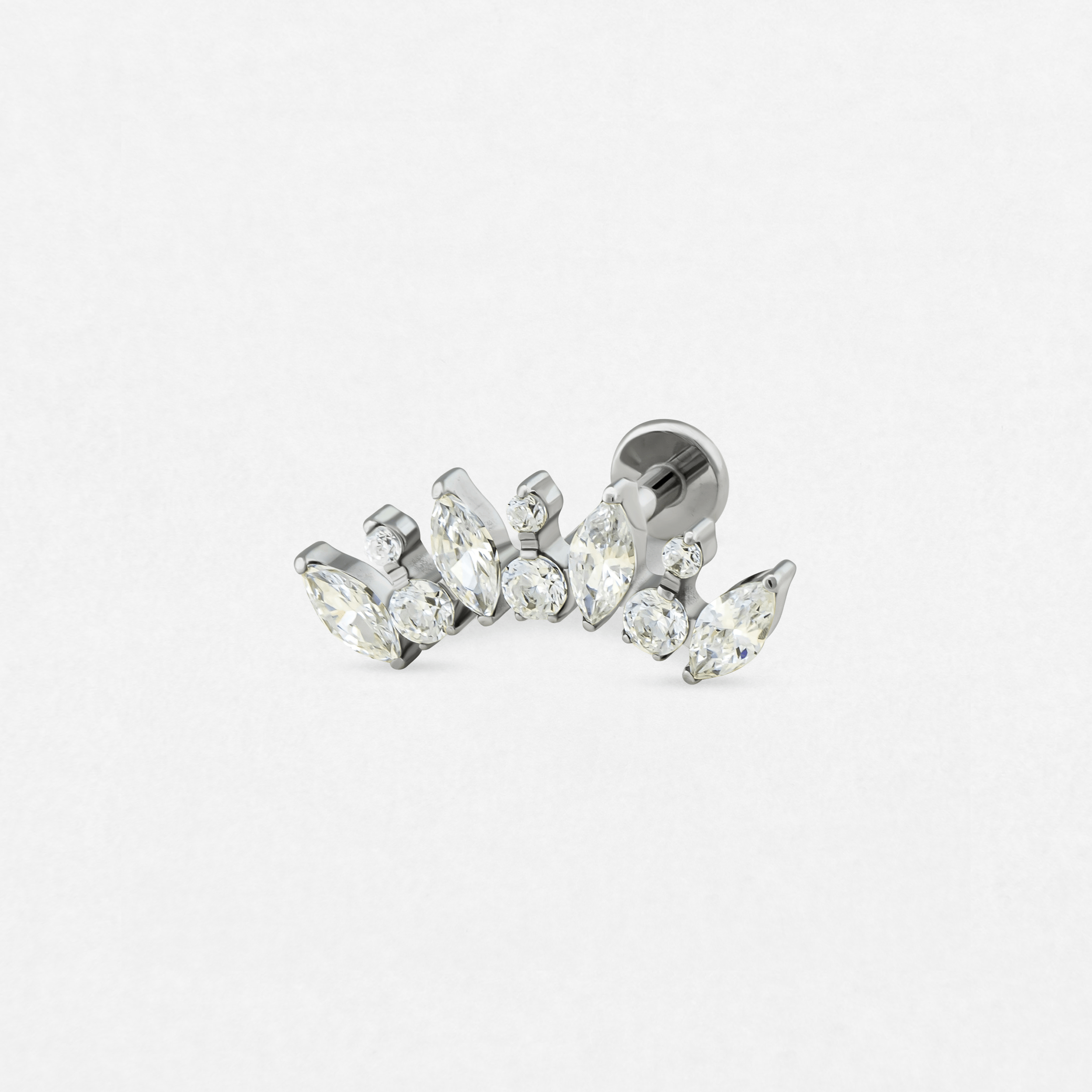 El modelo «Apolo» de Titanio-Noble Art es un pendiente de botón de plata con piedras preciosas transparentes de talla marquesa y redonda, con un diseño curvo, que se muestra sobre un fondo blanco.