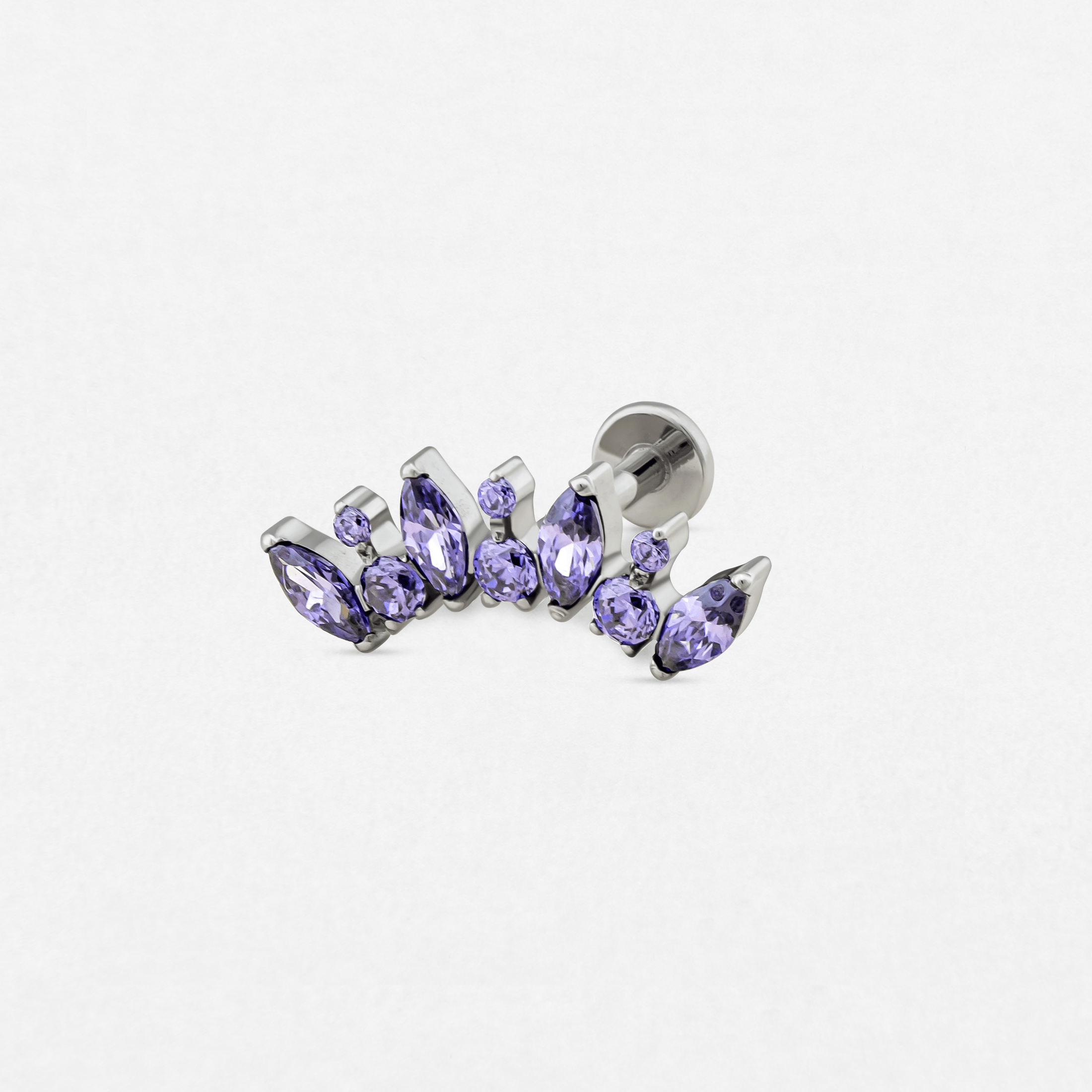El modelo «Apolo» de Titanio-Noble Art es un pendiente de botón de plata con un ingenioso conjunto de piedras preciosas moradas de diversas formas, que refleja un estilo distintivo de piercing y destaca sobre un fondo blanco liso.