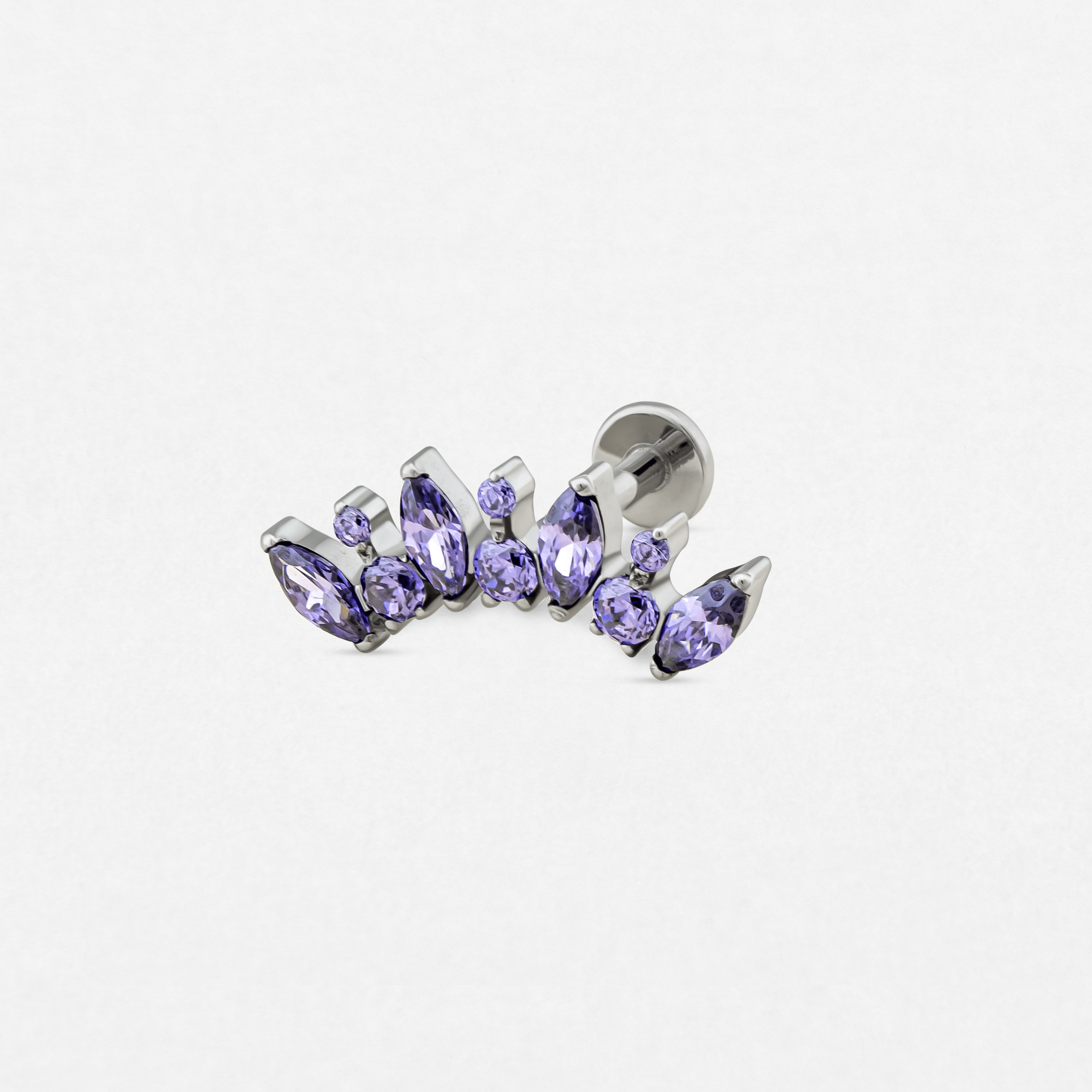 El modelo «Apolo» de Titanio-Noble Art es un pendiente de botón de plata con un ingenioso conjunto de piedras preciosas moradas de diversas formas, que refleja un estilo distintivo de piercing y destaca sobre un fondo blanco liso.