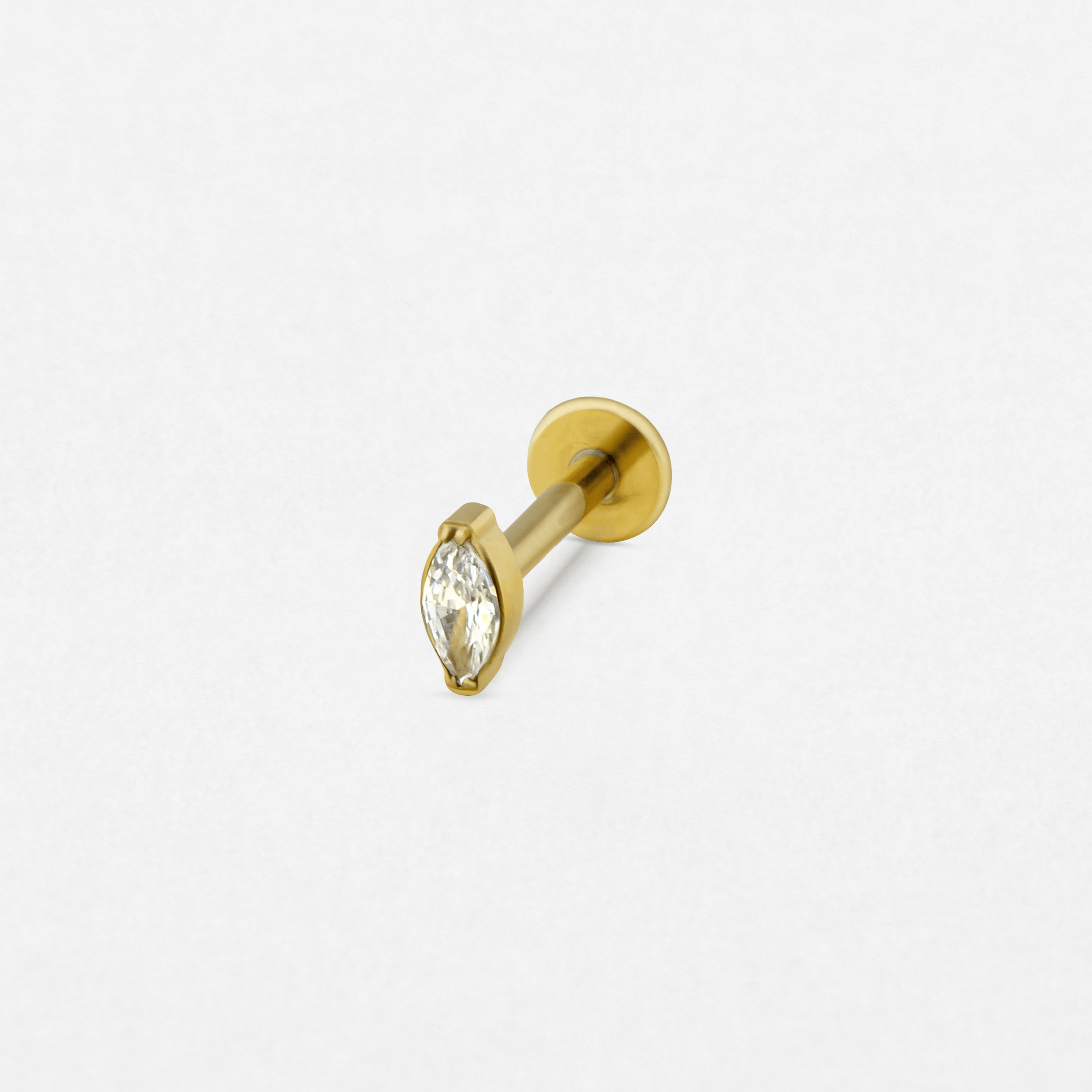 El pendiente labret de oro «Aria» de Titanio-Noble Art presenta una piedra preciosa transparente de talla marquesa engastada con garras, que destaca sobre un fondo blanco liso.