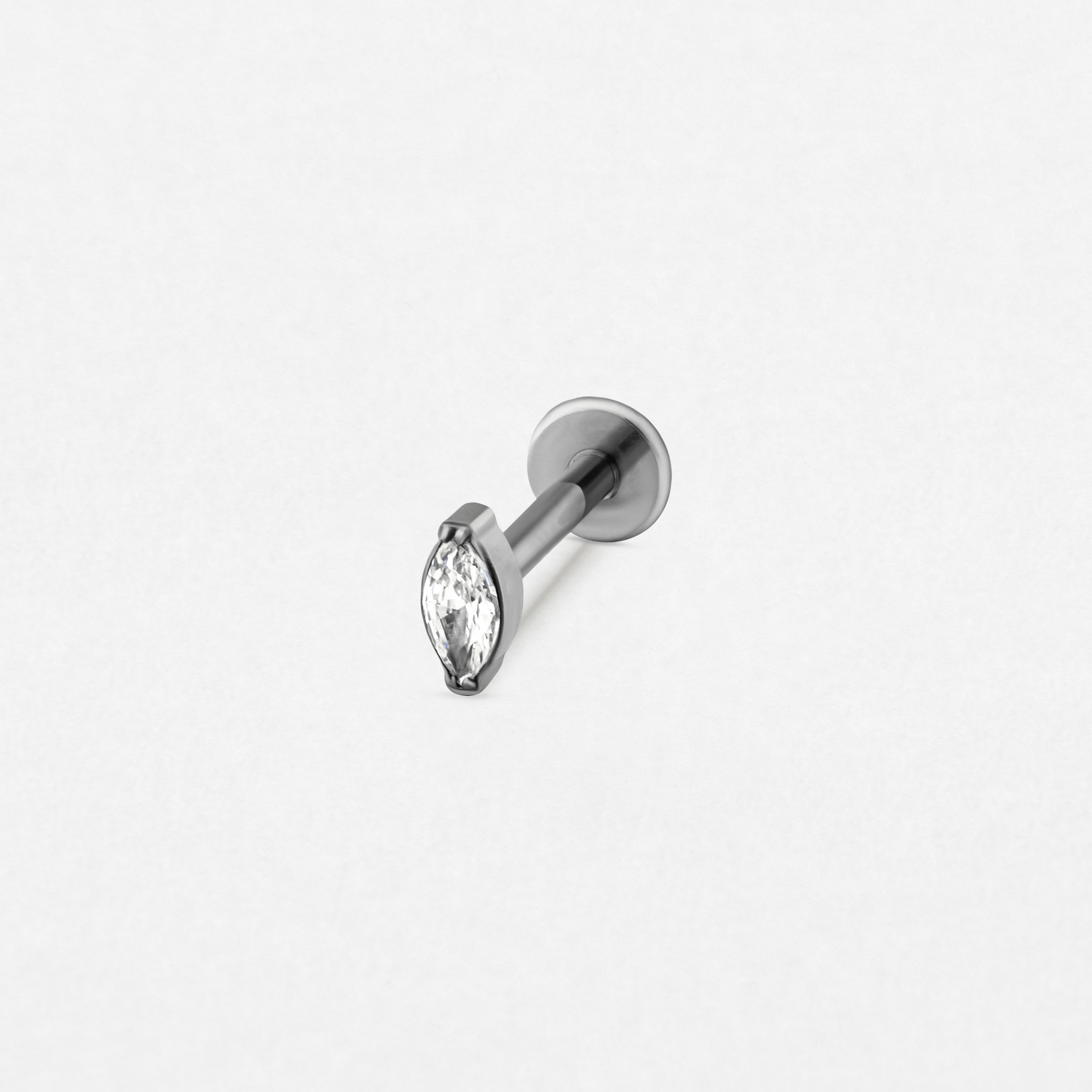 El pendiente «Aria» de Titanio-Noble Art presenta un pendiente minimalista de plata con una gema transparente en forma de marquesa engastada con garras metálicas y un cierre plano, que se muestra sobre un fondo blanco liso.