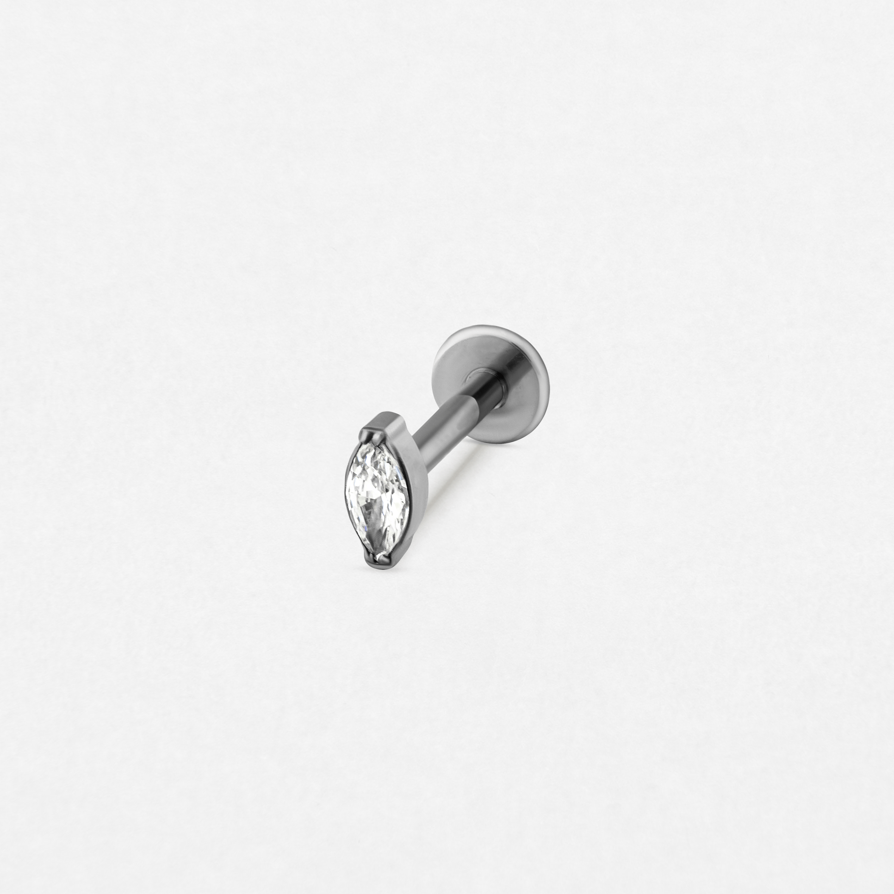El pendiente «Aria» de Titanio-Noble Art presenta un pendiente minimalista de plata con una gema transparente en forma de marquesa engastada con garras metálicas y un cierre plano, que se muestra sobre un fondo blanco liso.