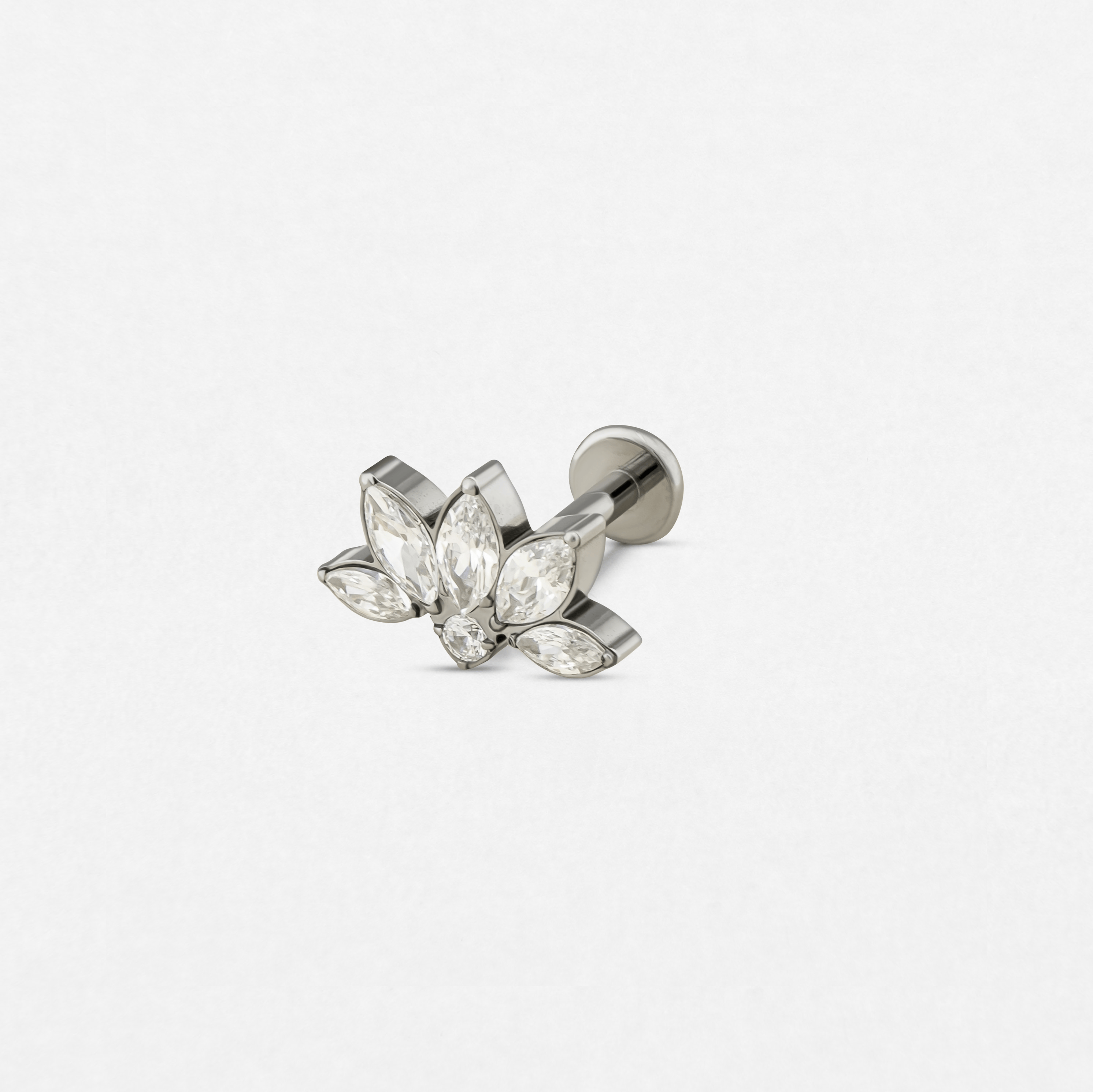 El pendiente de botón de plata «Ava», de Titanio-Noble Art, presenta un diseño de flor de loto con piedras preciosas transparentes de talla marquesa a modo de pétalos, un toque elegante para tu piercing, que se muestra sobre un fondo blanco liso.