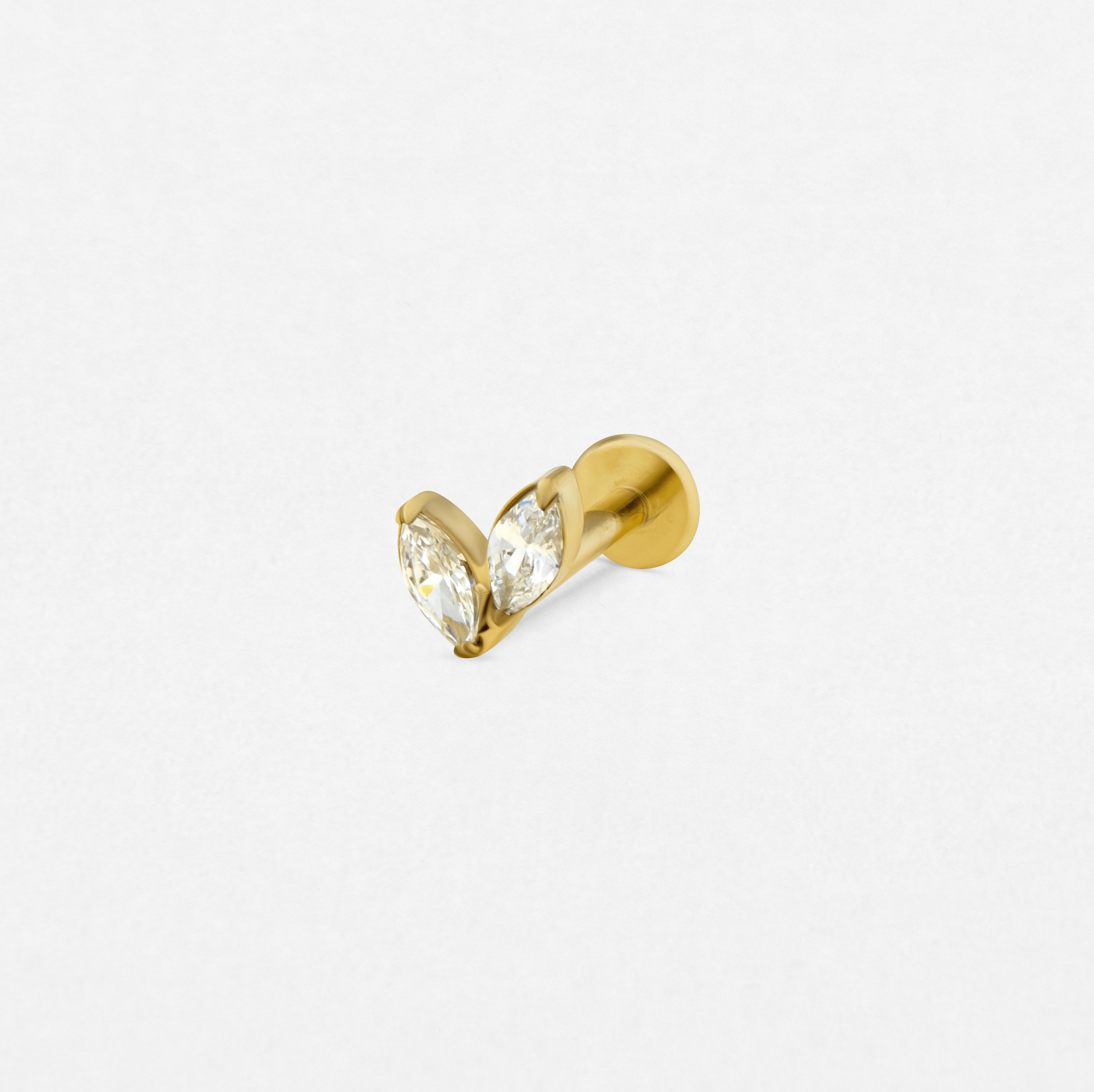 El pendiente de botón «Creta Gold» de Titanio - Noble Art cuenta con dos piedras preciosas transparentes de talla marquesa dispuestas en forma de V, que desprenden una elegancia refinada sobre un fondo blanco.