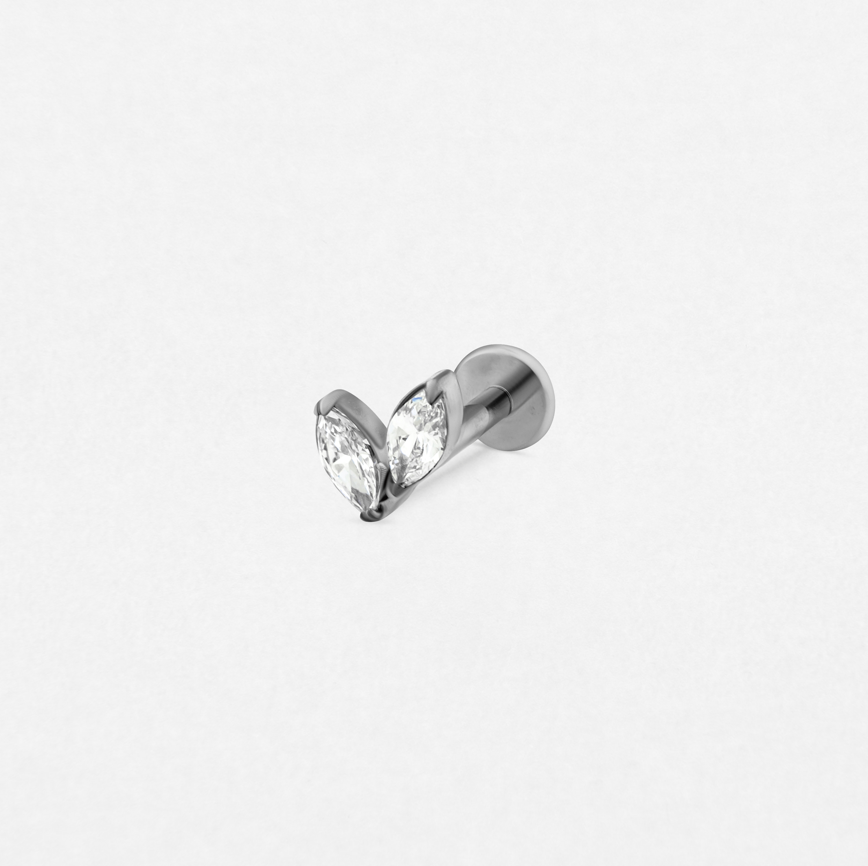 El pendiente «Creta» de Titanio-Noble Art cuenta con dos piedras preciosas transparentes de talla marquesa dispuestas en forma de corazón y engastadas en un pendiente de plata, que destacan con elegancia sobre un fondo blanco liso.