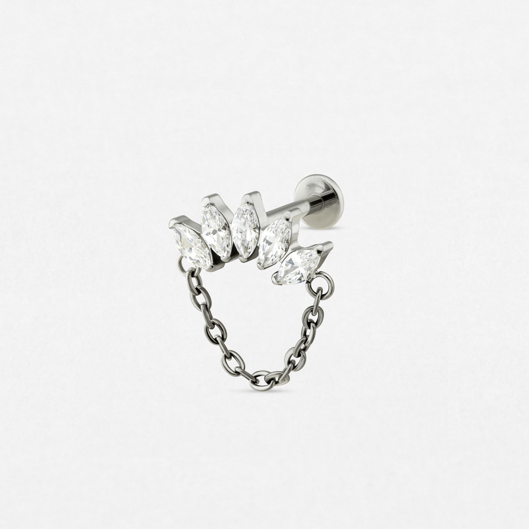 El pendiente «Electra» de Titanio-Noble Art es un pendiente de botón de plata con cinco piedras preciosas transparentes de talla marquesa dispuestas en fila, unidas a una cadena colgante decorativa, que se muestra sobre un fondo blanco liso.