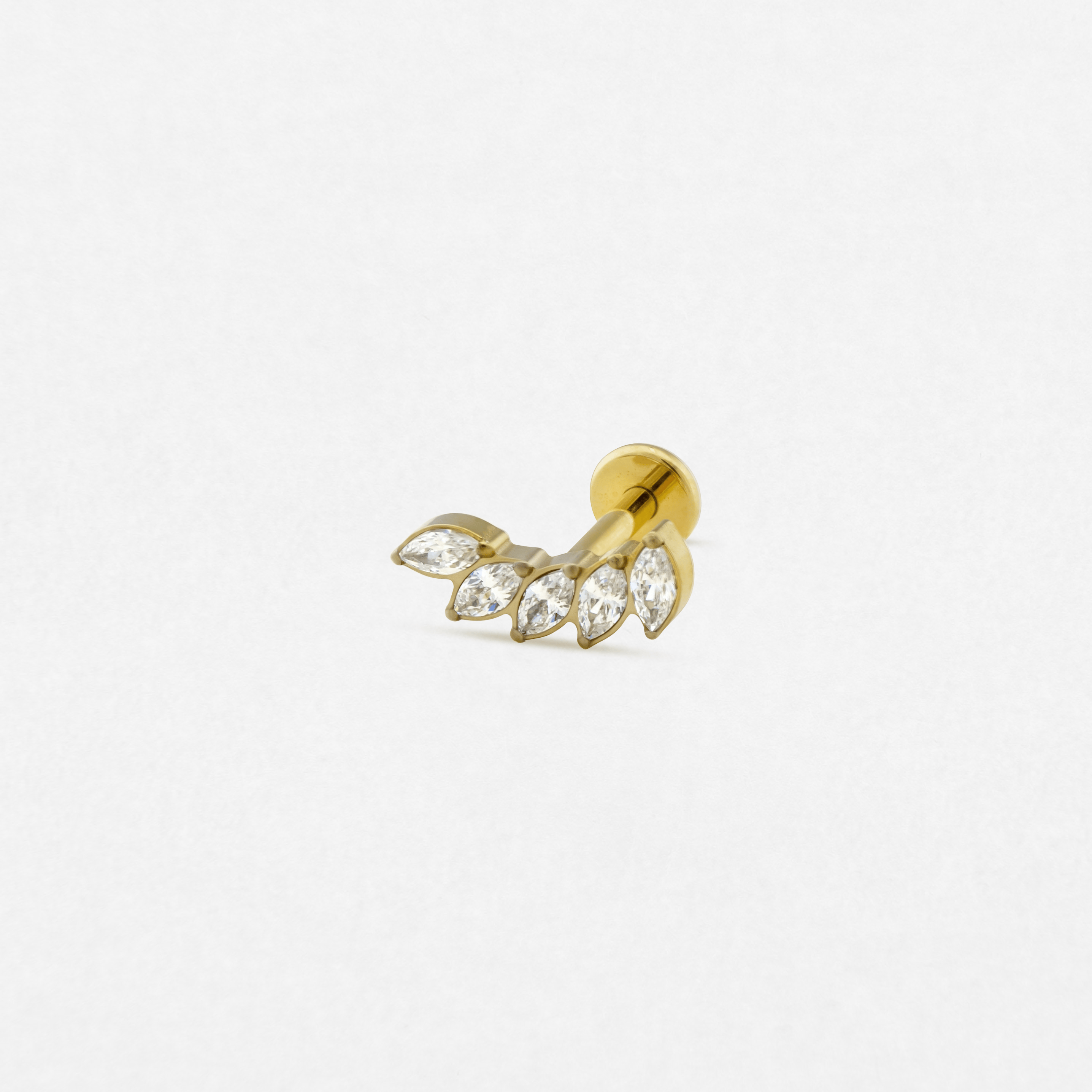 El pendiente «Gia dorado» de Titanio-Noble Art cuenta con cinco piedras preciosas transparentes de talla marquesa dispuestas en un racimo inspirado en una hoja, lo que le confiere una elegancia refinada; es ideal para quienes deseen ampliar su colección de joyas o piercings.