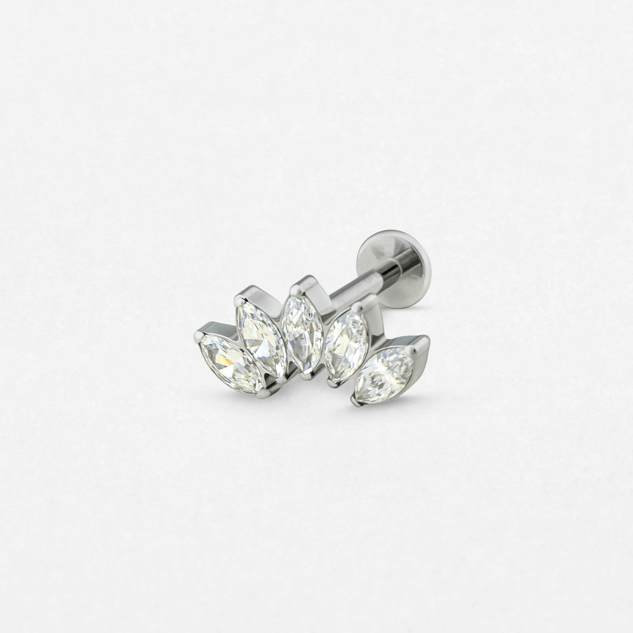 El modelo «Titanio- Noble Art Marquise 5 cz blanca» es un pendiente de botón de plata con cinco piedras transparentes de talla marquesa dispuestas en forma de racimo con forma de hoja, perfecto para tu próximo piercing y presentado sobre un fondo blanco liso.