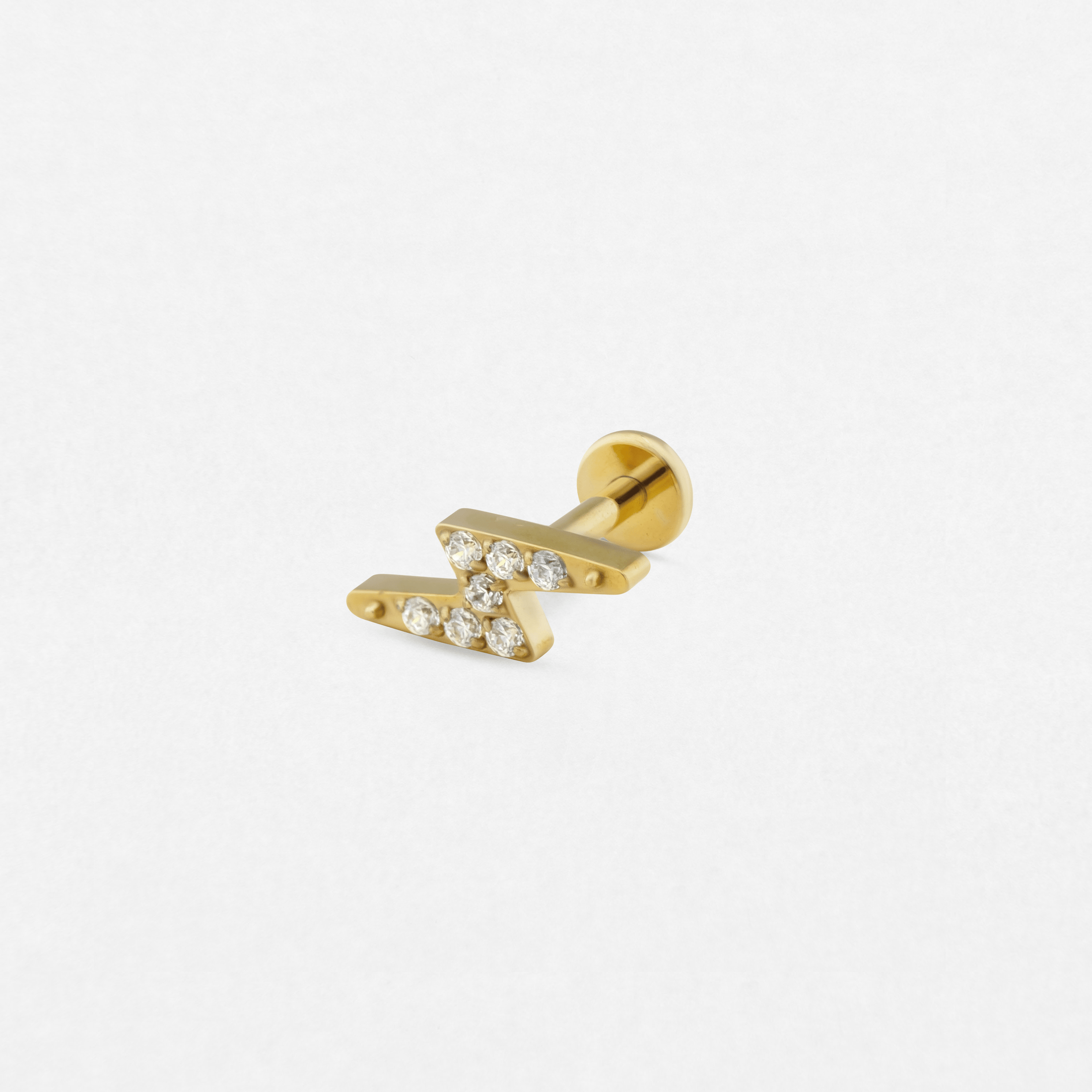 El labret de oro de estilo maya de Titanio-Noble Art presenta un diseño en forma de rayo en zigzag con pequeñas piedras preciosas transparentes, lo que resalta su elegancia sobre un fondo blanco liso.