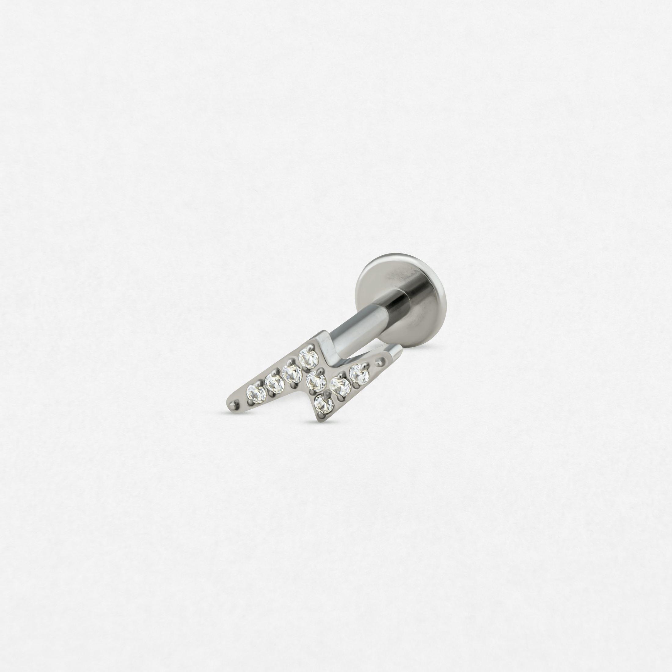 El pendiente «Maya» de Titanio-Noble Art es un pendiente de botón de plata con cierre plano, que presenta un diseño en forma de N con piedras preciosas transparentes incrustadas, sobre un fondo blanco liso.