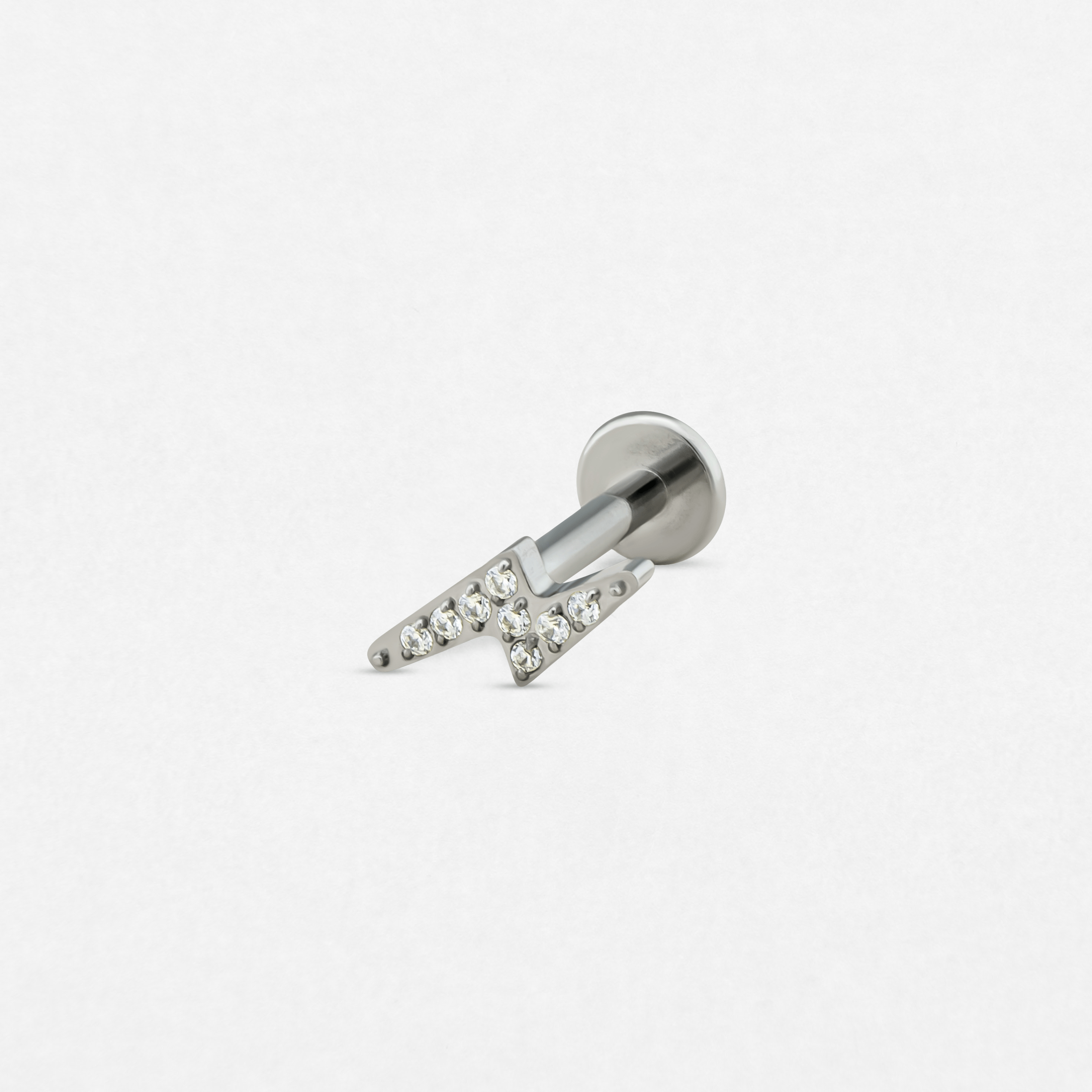 El pendiente «Maya» de Titanio-Noble Art es un pendiente de botón de plata con cierre plano, que presenta un diseño en forma de N con piedras preciosas transparentes incrustadas, sobre un fondo blanco liso.