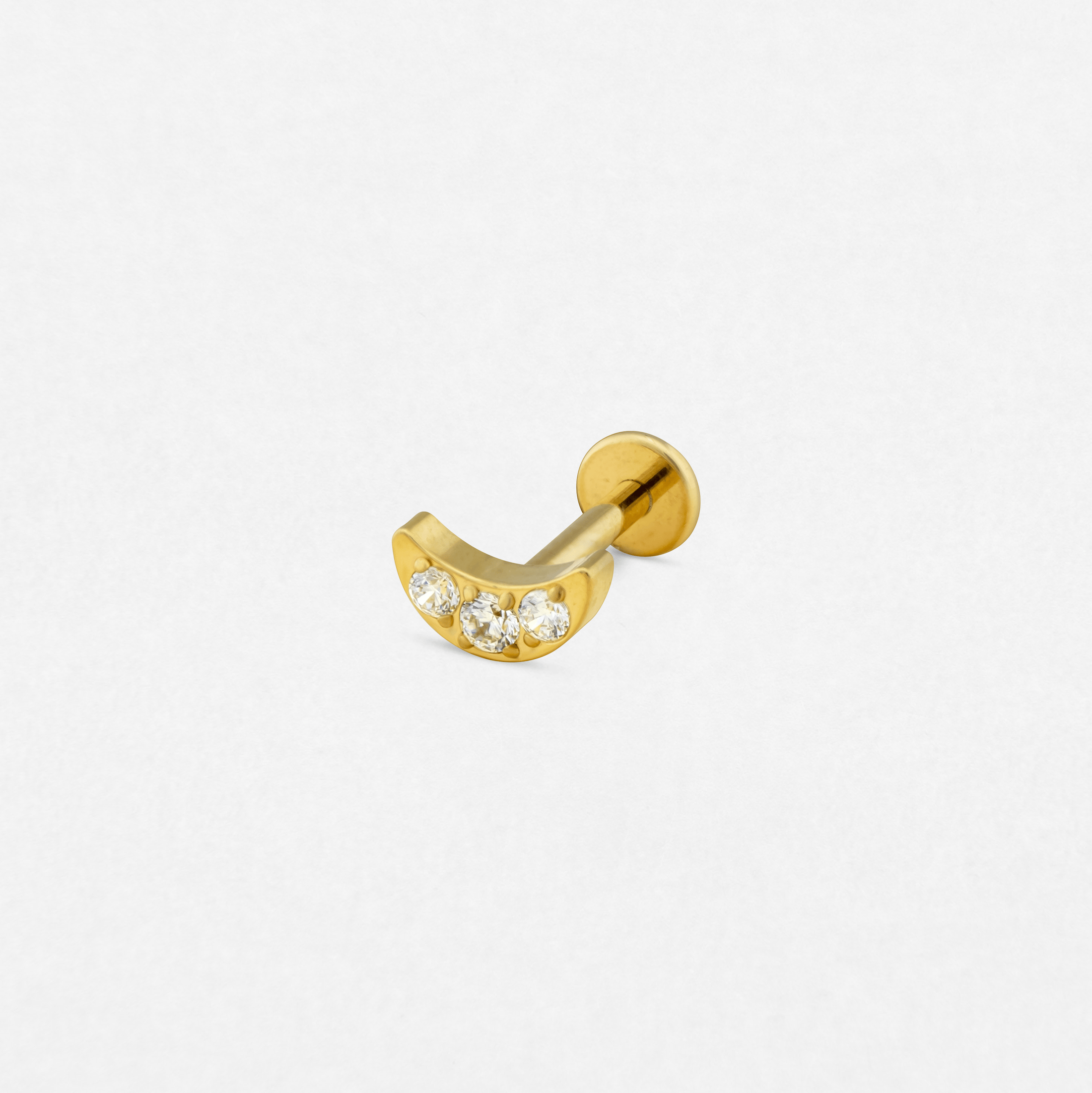 El pendiente «Moon cz» de la colección Titanio-Noble Art es una barra curvada de oro con tres pequeños diamantes redondos en la parte delantera, que se muestra sobre un fondo blanco: una opción refinada para expresarse con elegancia.