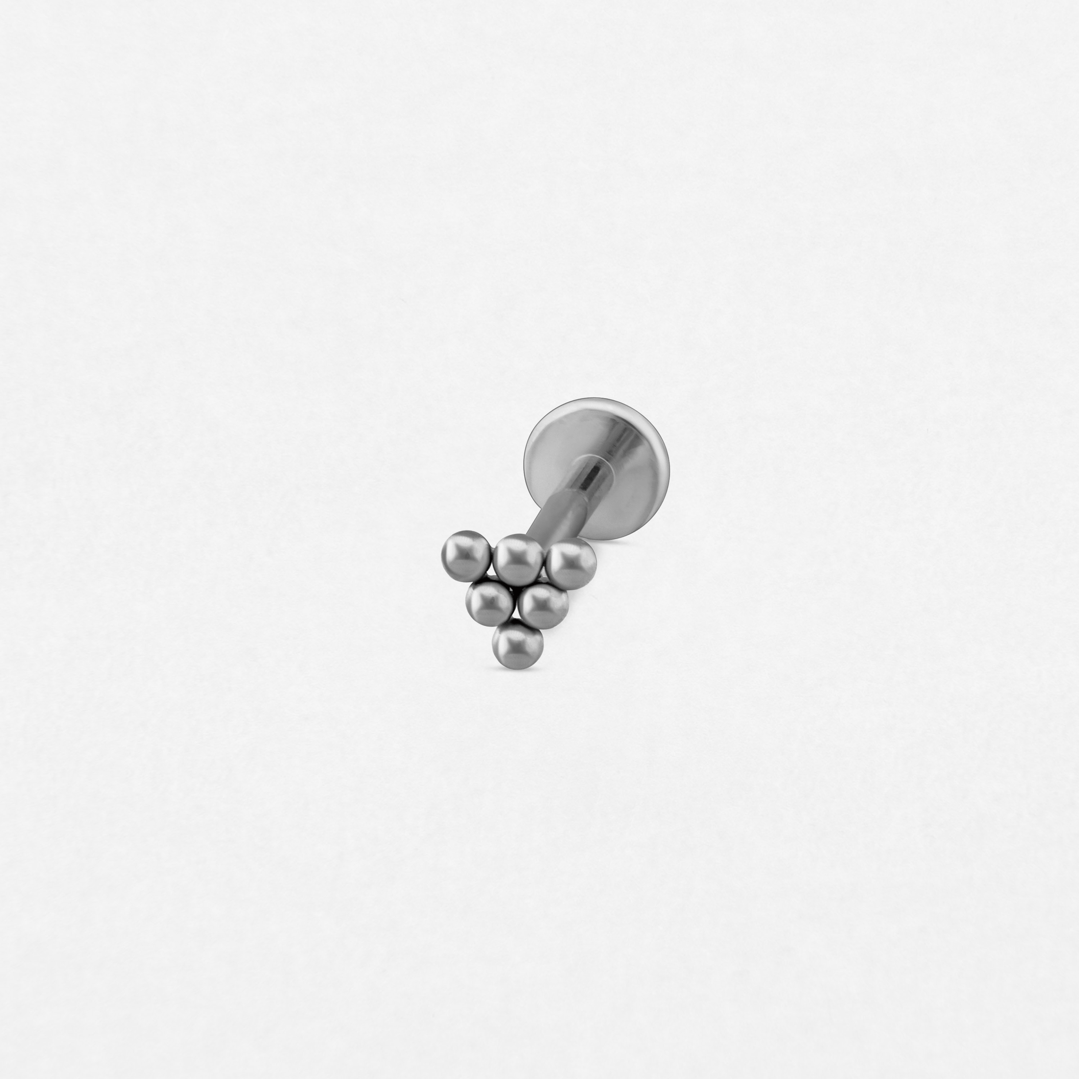 El pendiente tipo labret «Piramide» de Titanio-Noble Art es un pequeño pendiente de plata para piercing que presenta seis cuentas metálicas dispuestas en un racimo triangular, sobre un fondo blanco liso.