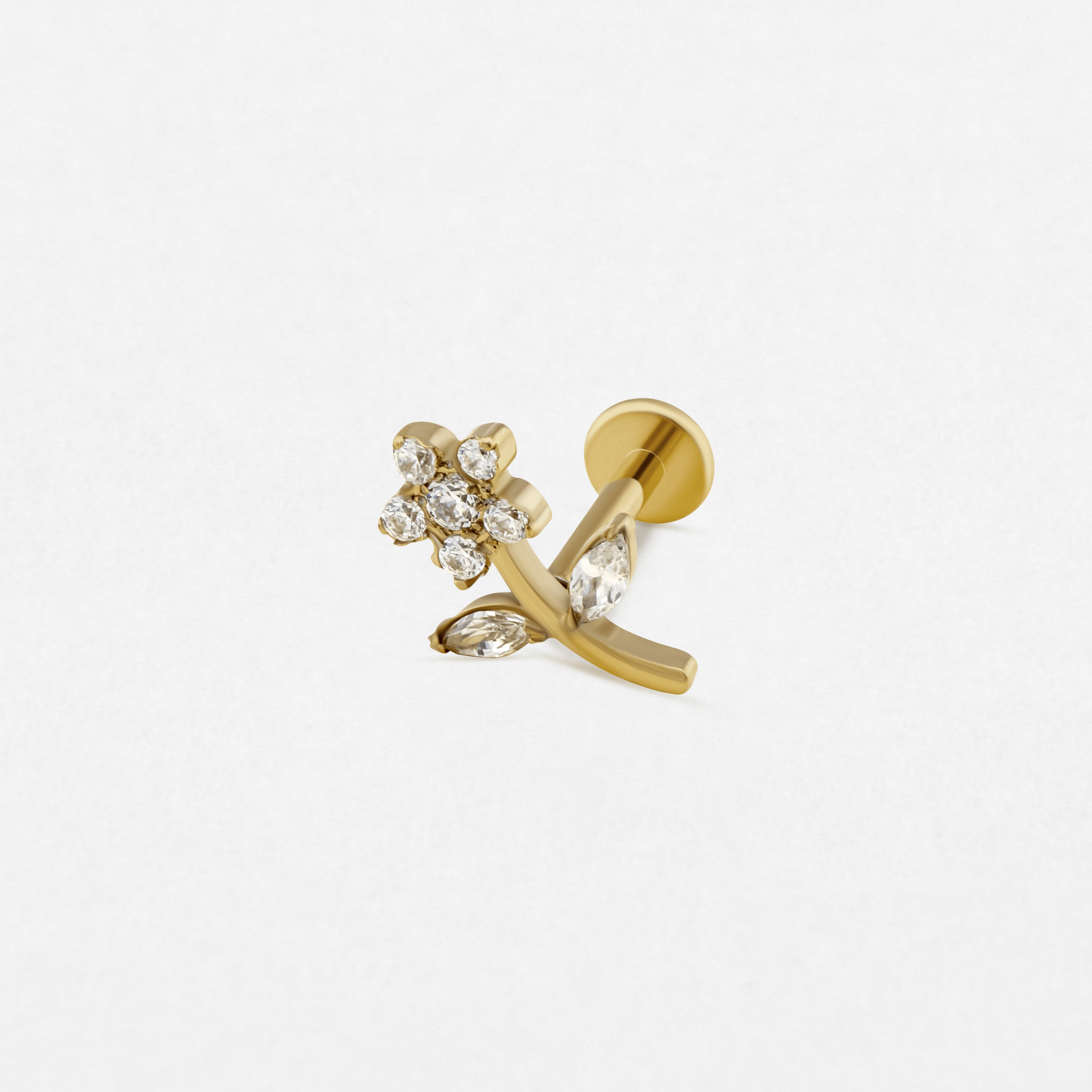El pendiente de botón «Selena» de Titanio-Noble Art presenta una flor dorada con un tallo curvado, decorada con piedras preciosas transparentes en los pétalos y las hojas. Ideal para los amantes de los piercings. Se muestra sobre un fondo blanco liso.