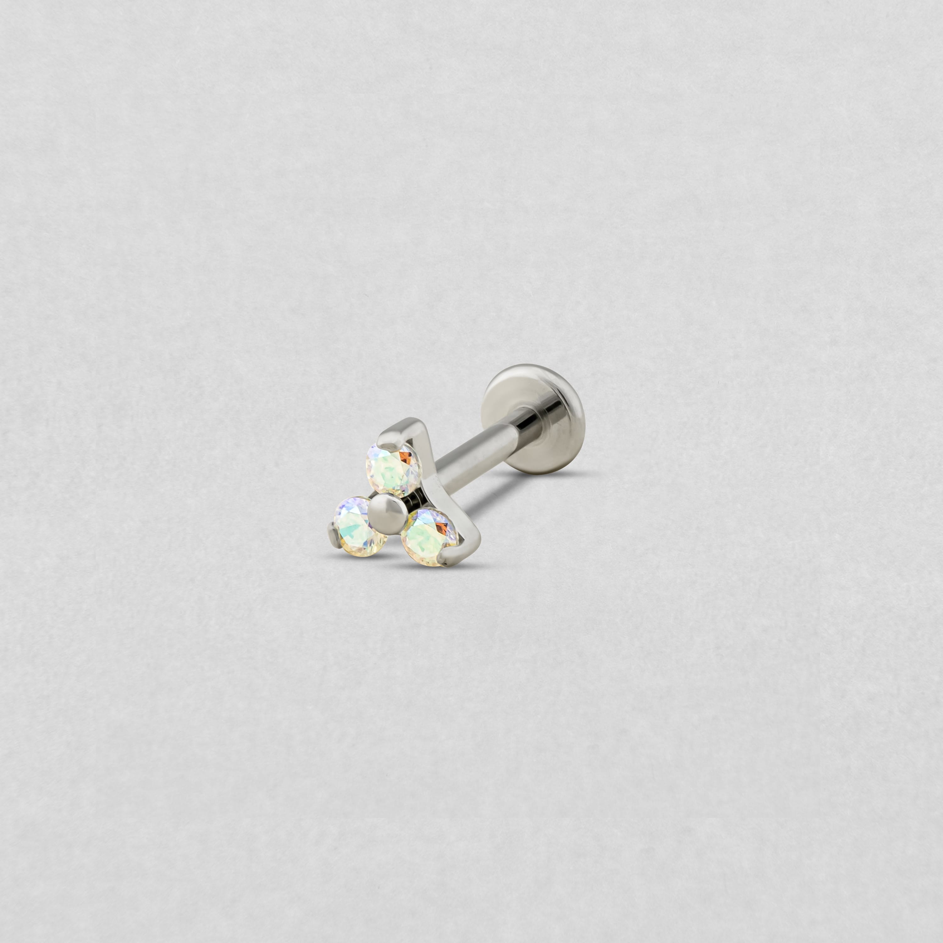 Los pendientes tipo barra «Trinity cz» de Titanio-Noble Art cuentan con tres pequeñas piedras preciosas iridiscentes dispuestas en forma de triángulo sobre un fondo gris claro.