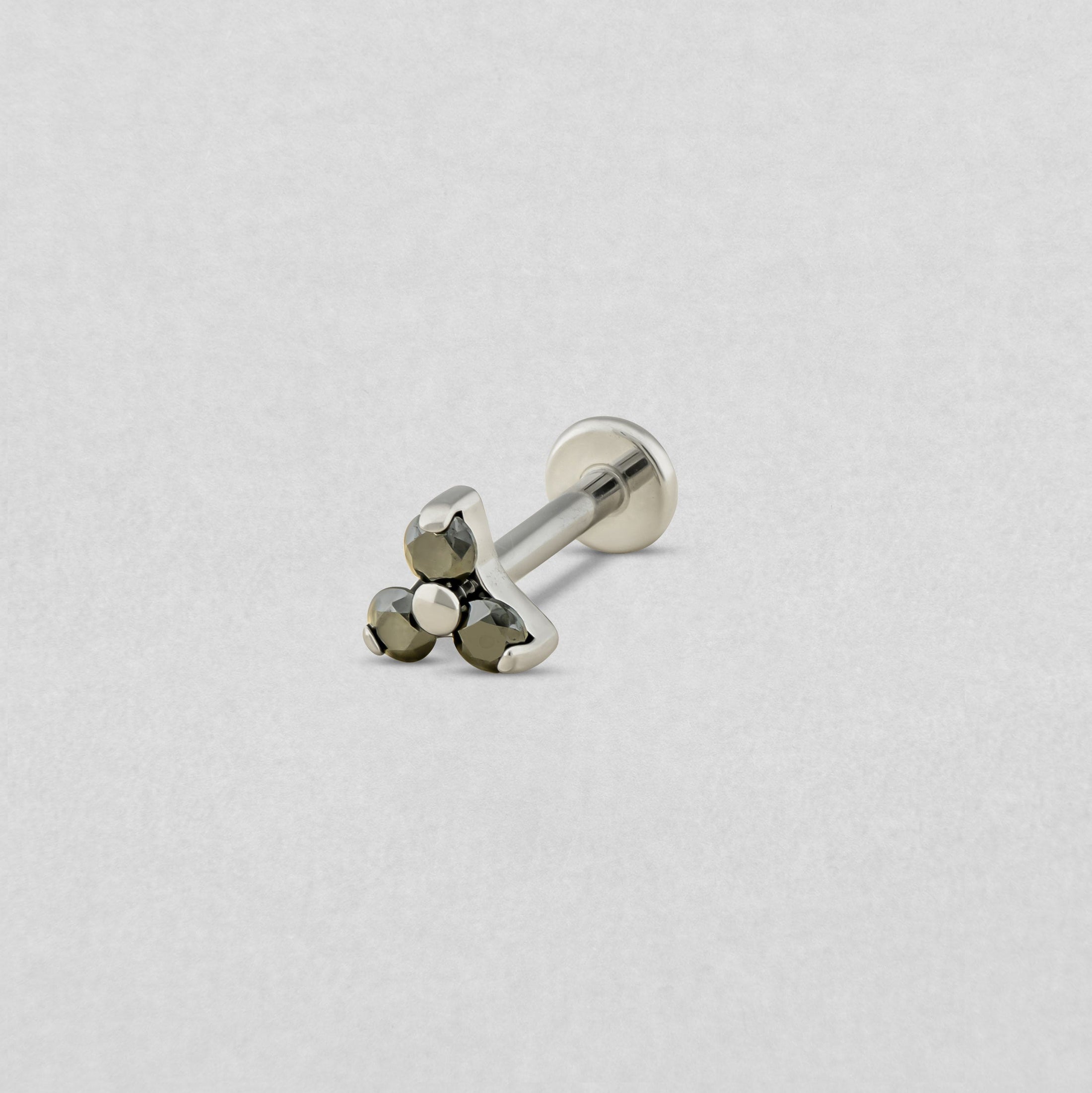 Das Modell «Trinity cz» von Titanium-Noble Art ist ein silberner Knopf-Ohrstecker mit flachem Verschluss, verziert mit drei kleinen runden Metallperlen in Dreiecksform auf hellgrauem Hintergrund.