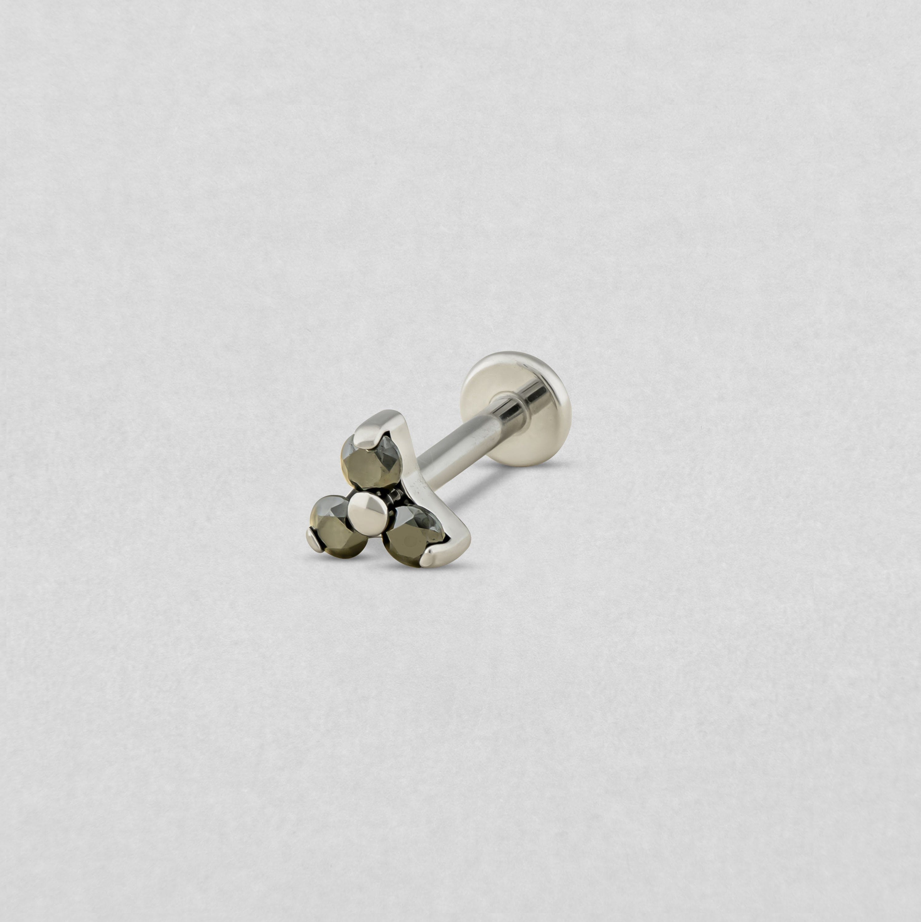 Das Modell «Trinity cz» von Titanium-Noble Art ist ein silberner Knopf-Ohrstecker mit flachem Verschluss, verziert mit drei kleinen runden Metallperlen in Dreiecksform auf hellgrauem Hintergrund.