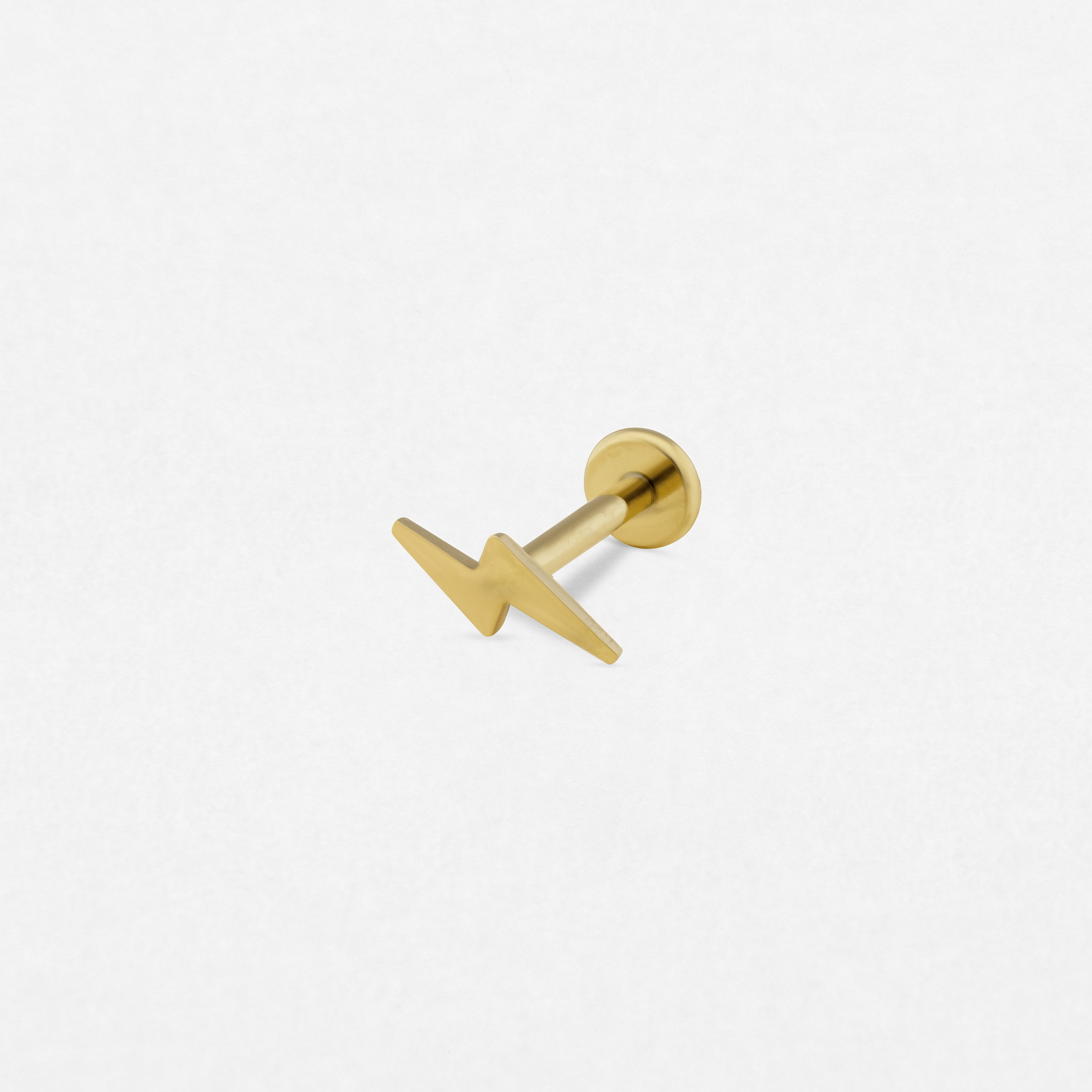 El pendiente de oro «Rayo» de Titanio-Noble Art presenta un diseño en forma de rayo, ideal para darle un toque atrevido a tu piercing. Se muestra sobre un fondo blanco liso.