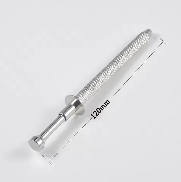 La herramienta de perforación ATRAPABOLAS de NOBLE ART BEAUTY SOCIEDAD LIMITADA, con un mango texturizado y una longitud de 120 mm, se muestra sobre un fondo blanco; es ideal para la perforación o la eliminación láser en el ámbito de la modificación corporal.
